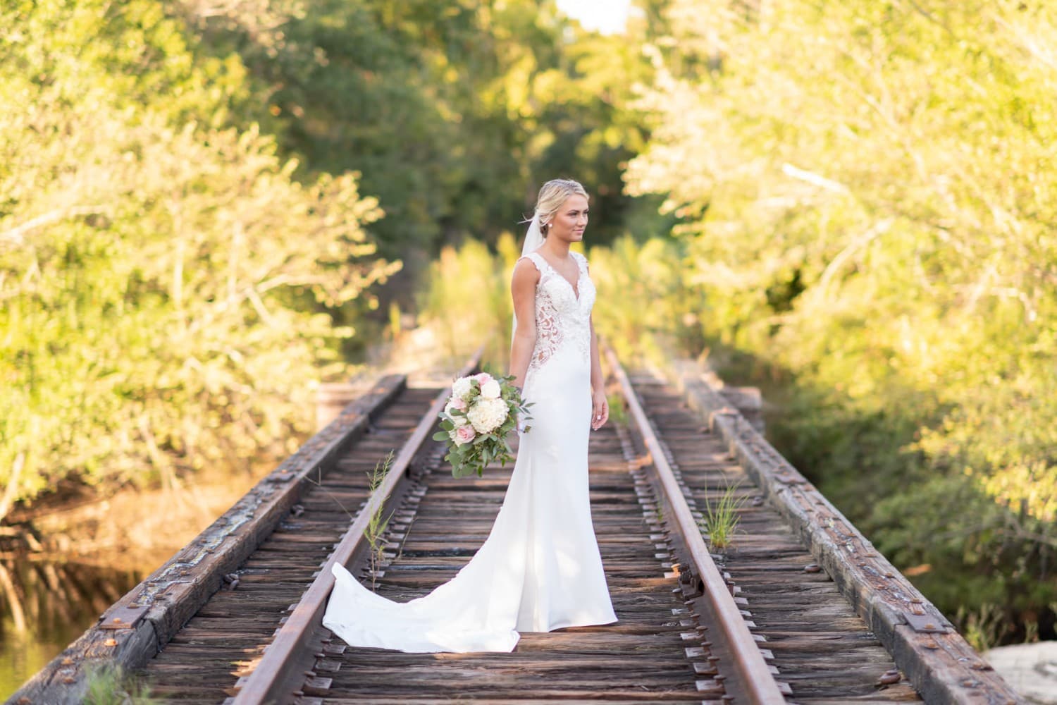 Bride standing on train tracks looking out on the river - Conway River Walk