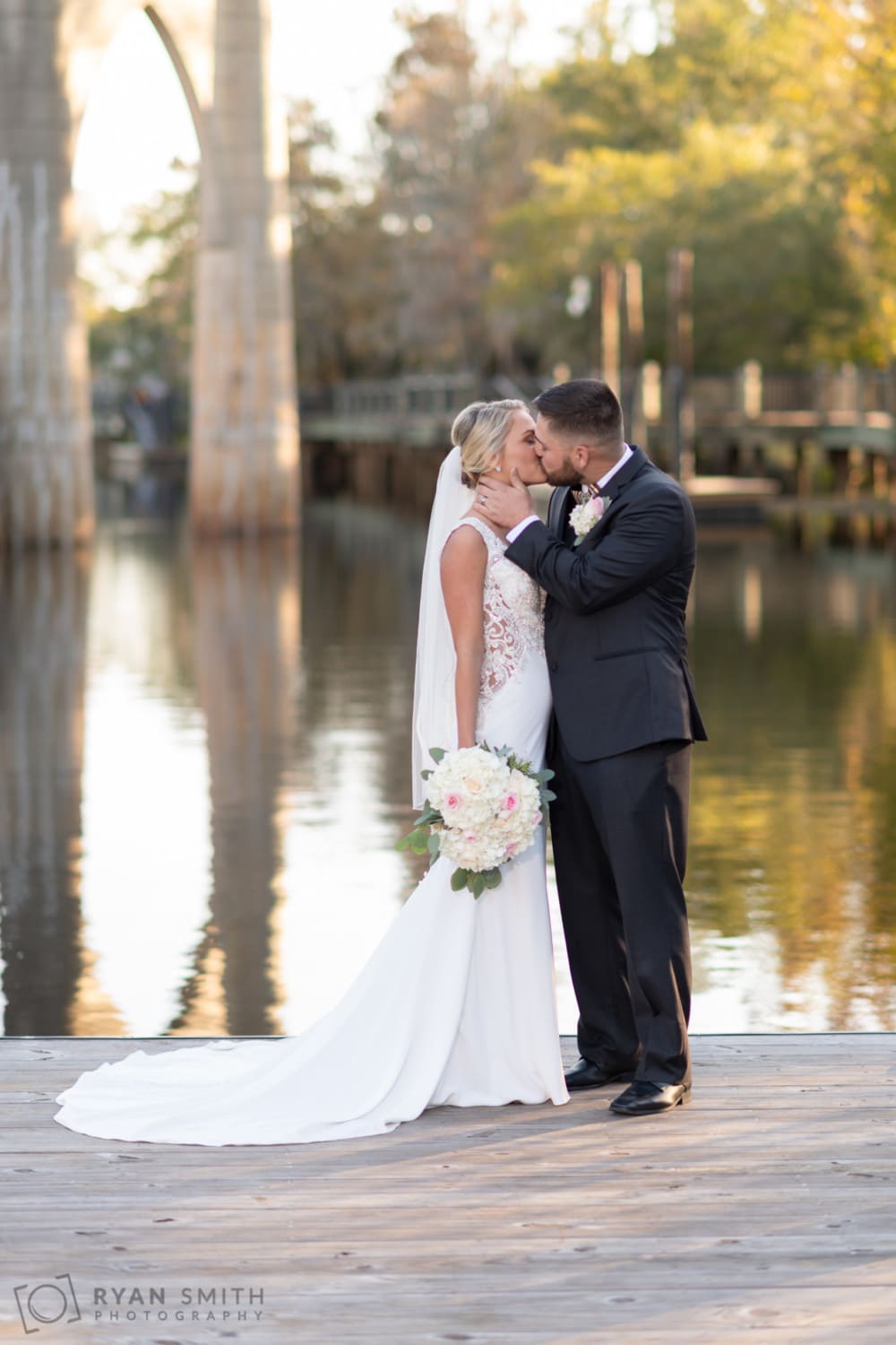 Bride and groom kissing on the Waccamaw River rock - Conway River Walk