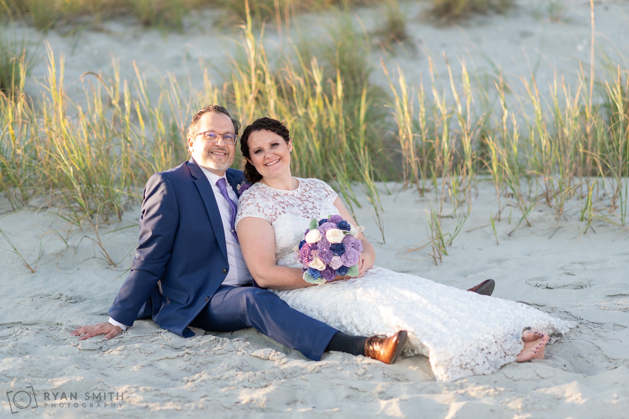 Bride and groom laying together by the dunes - North Beach Plantation