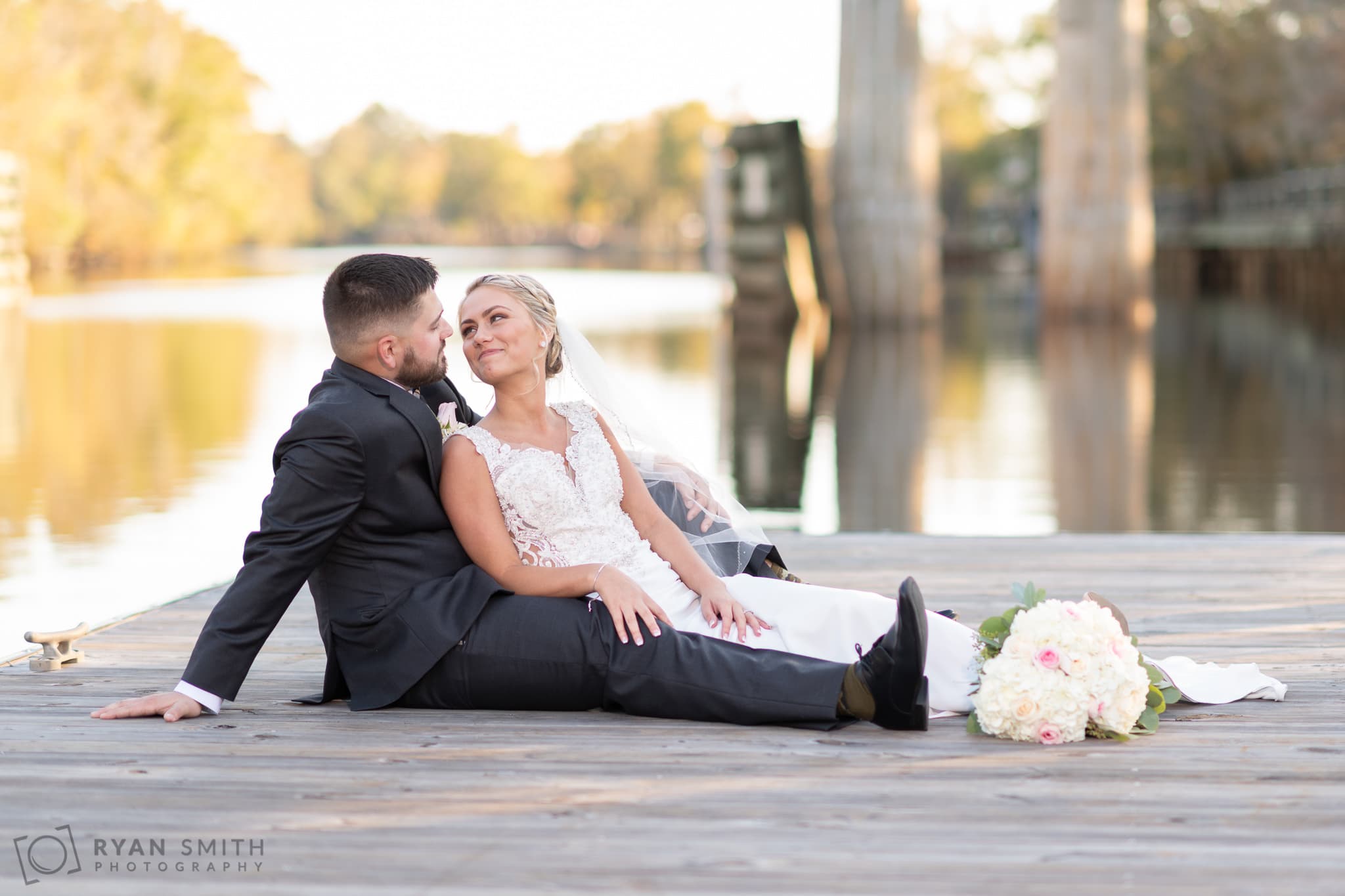 Bride and groom laying together on the river dock - Conway River Walk