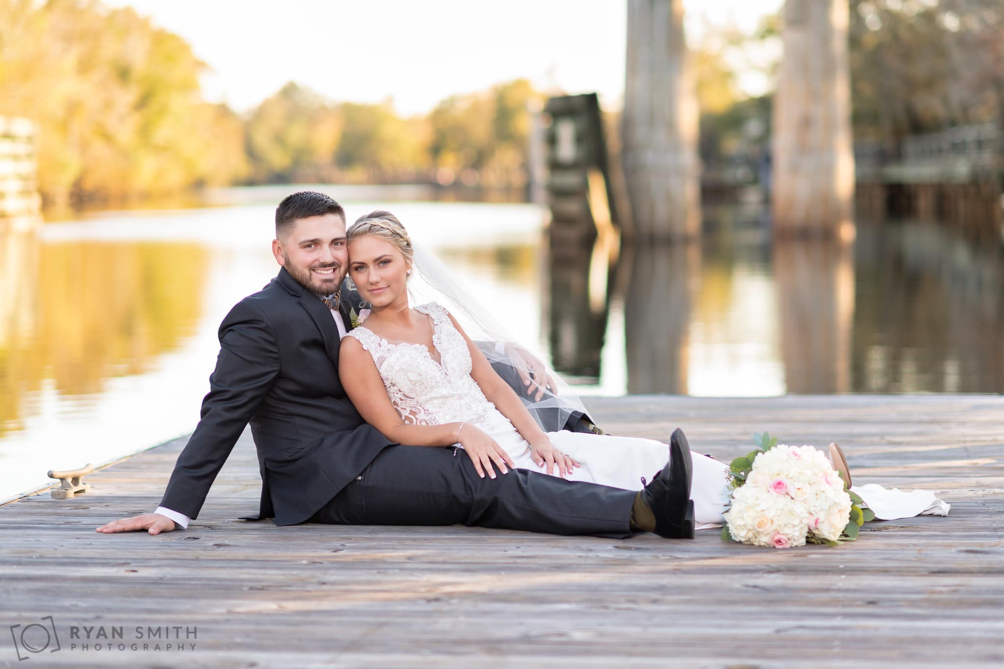 Bride and groom laying together on the river dock - Conway River Walk