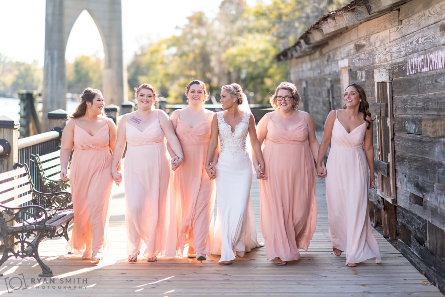Bridesmaids holding hands walking down the boardwalk - Conway River Walk