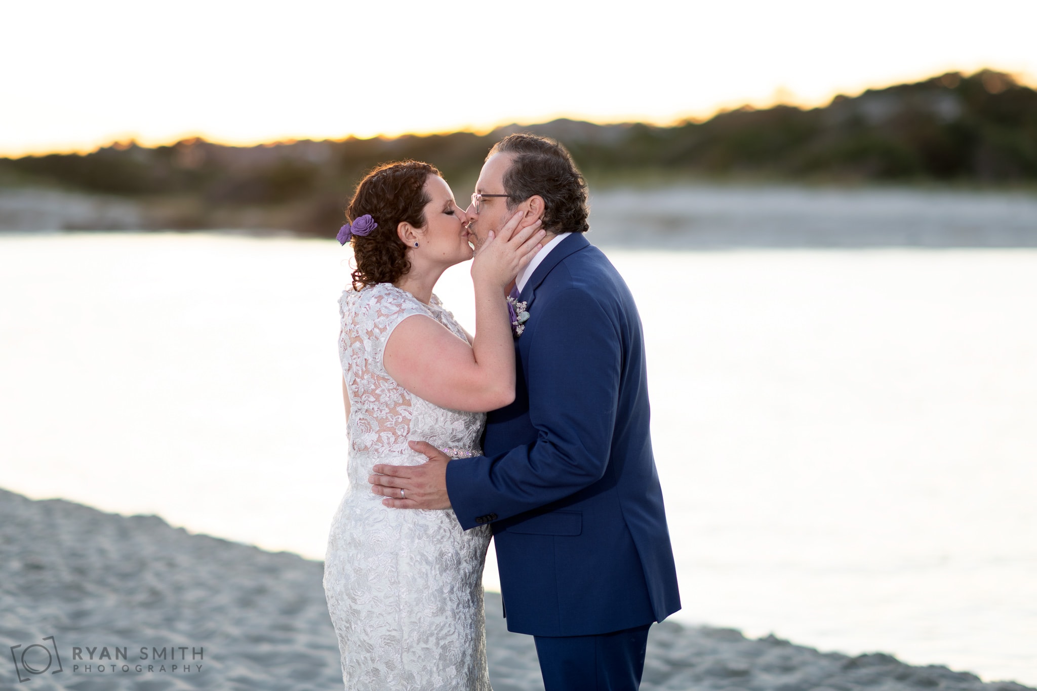 Pulling groom in for a kiss by the water - North Beach Plantation