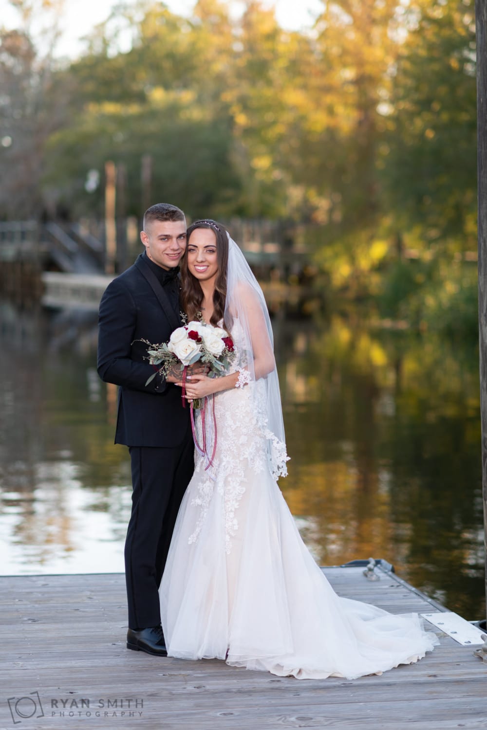 Bride and groom embracing on the dock by the water - Conway River Walk