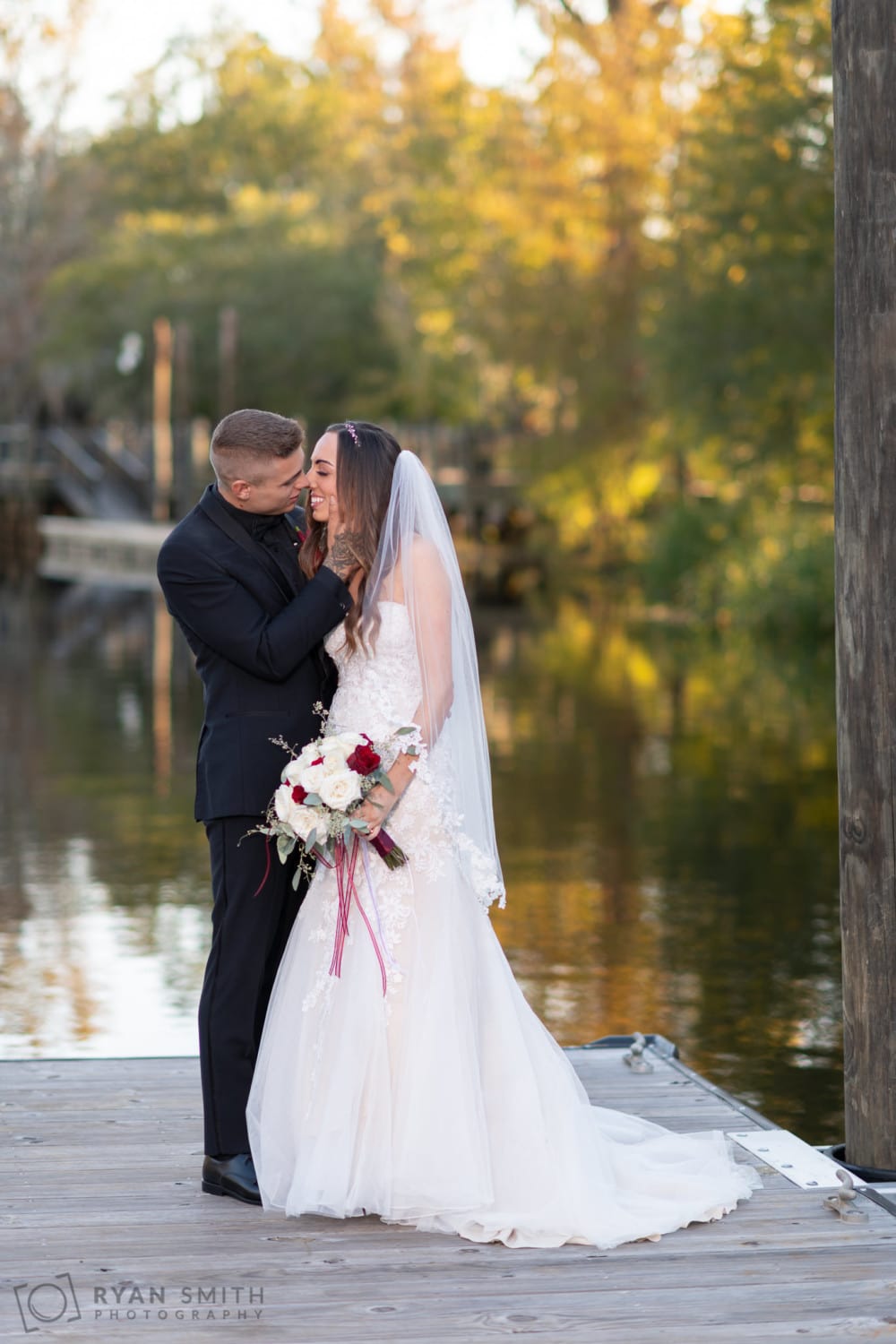 Bride and groom embracing on the dock by the water - Conway River Walk