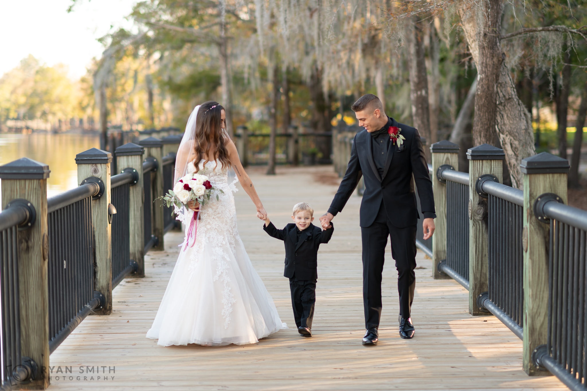 Bride and groom walking with their son down the boardwalk - Conway River Walk