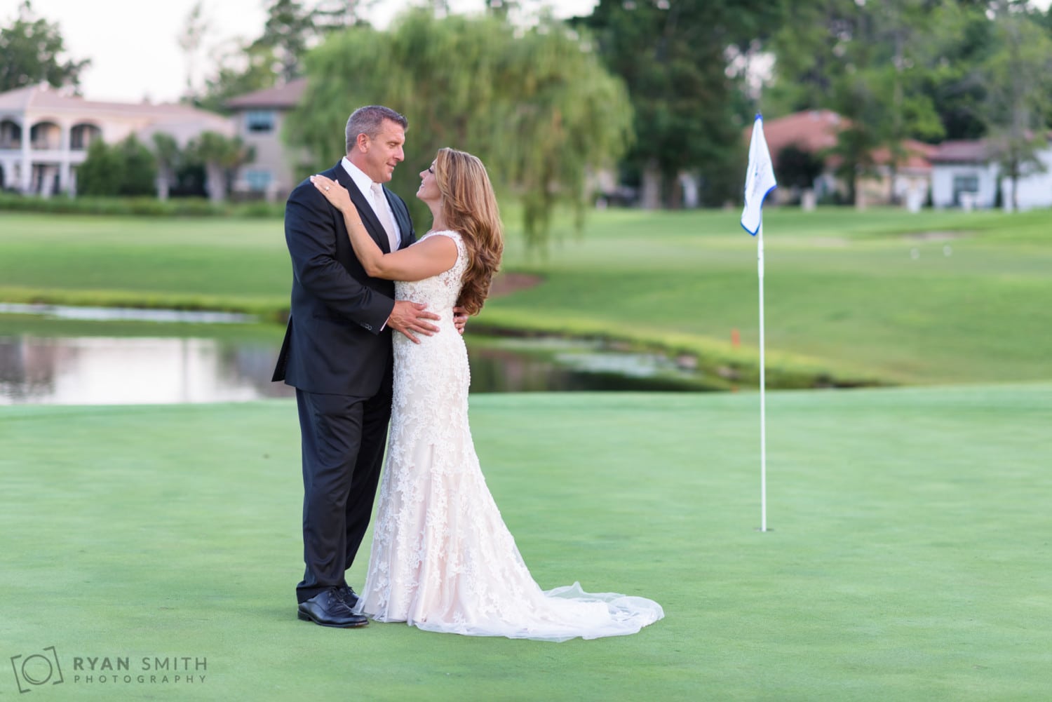 Bride and groom by the golf hole flag - Members Club at Grande Dunes