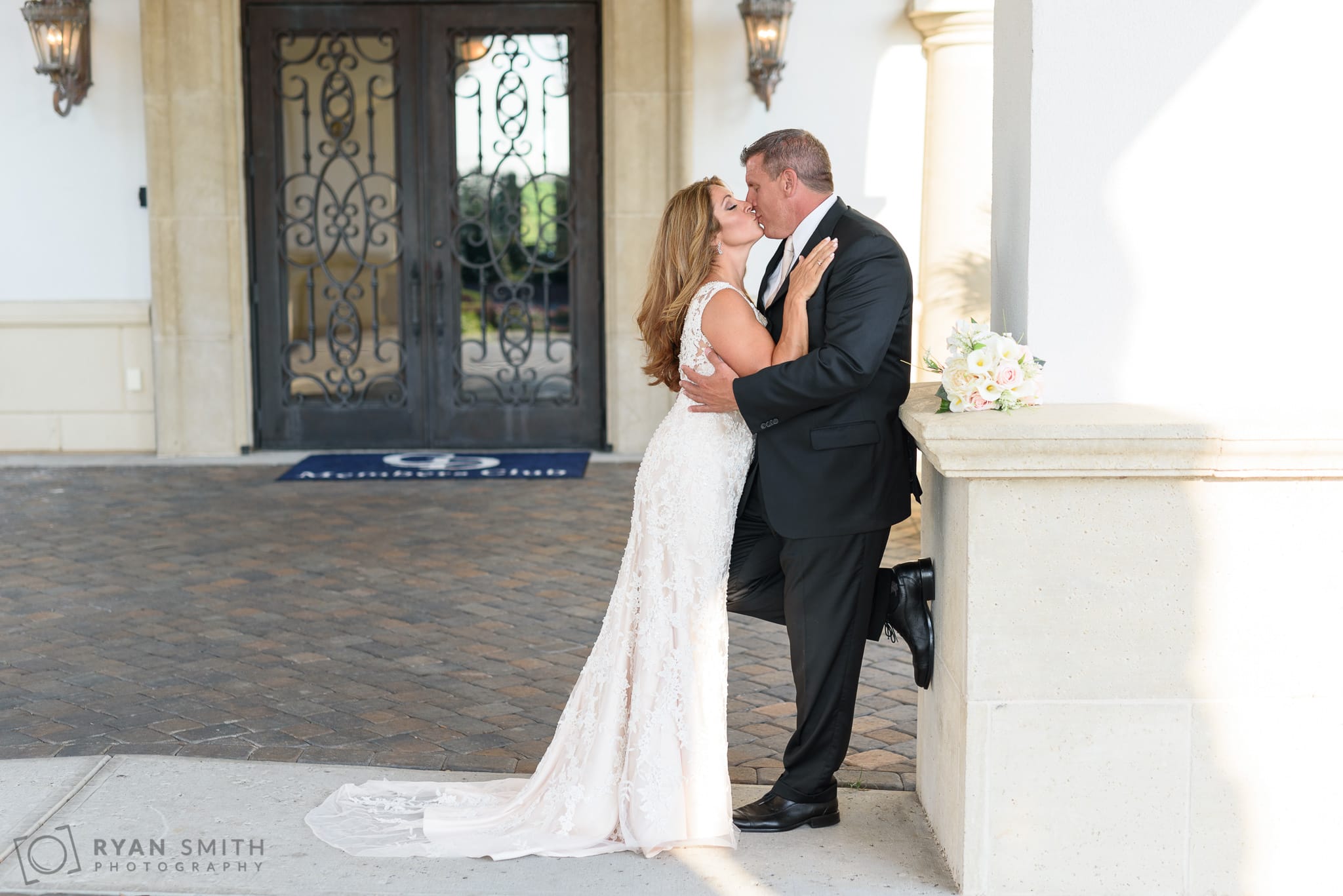 Bride and groom kissing by the column - Members Club at Grande Dunes