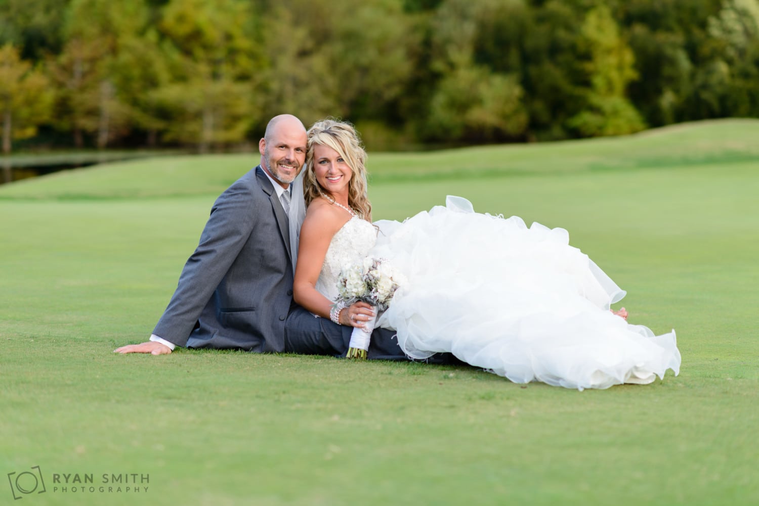 Bride and groom laying on the golf course together - Members Club at Grande Dunes