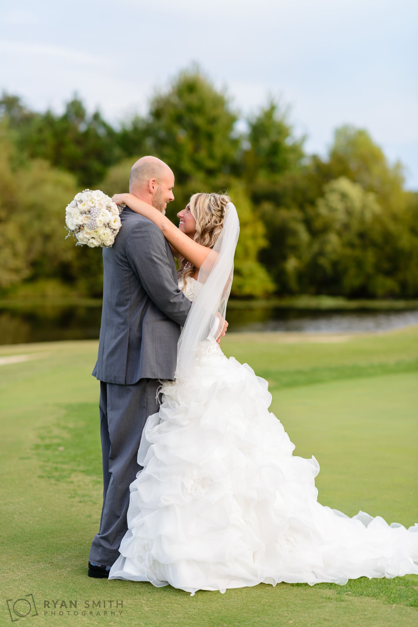 Bride and groom laying on the golf course together - Members Club at Grande Dunes