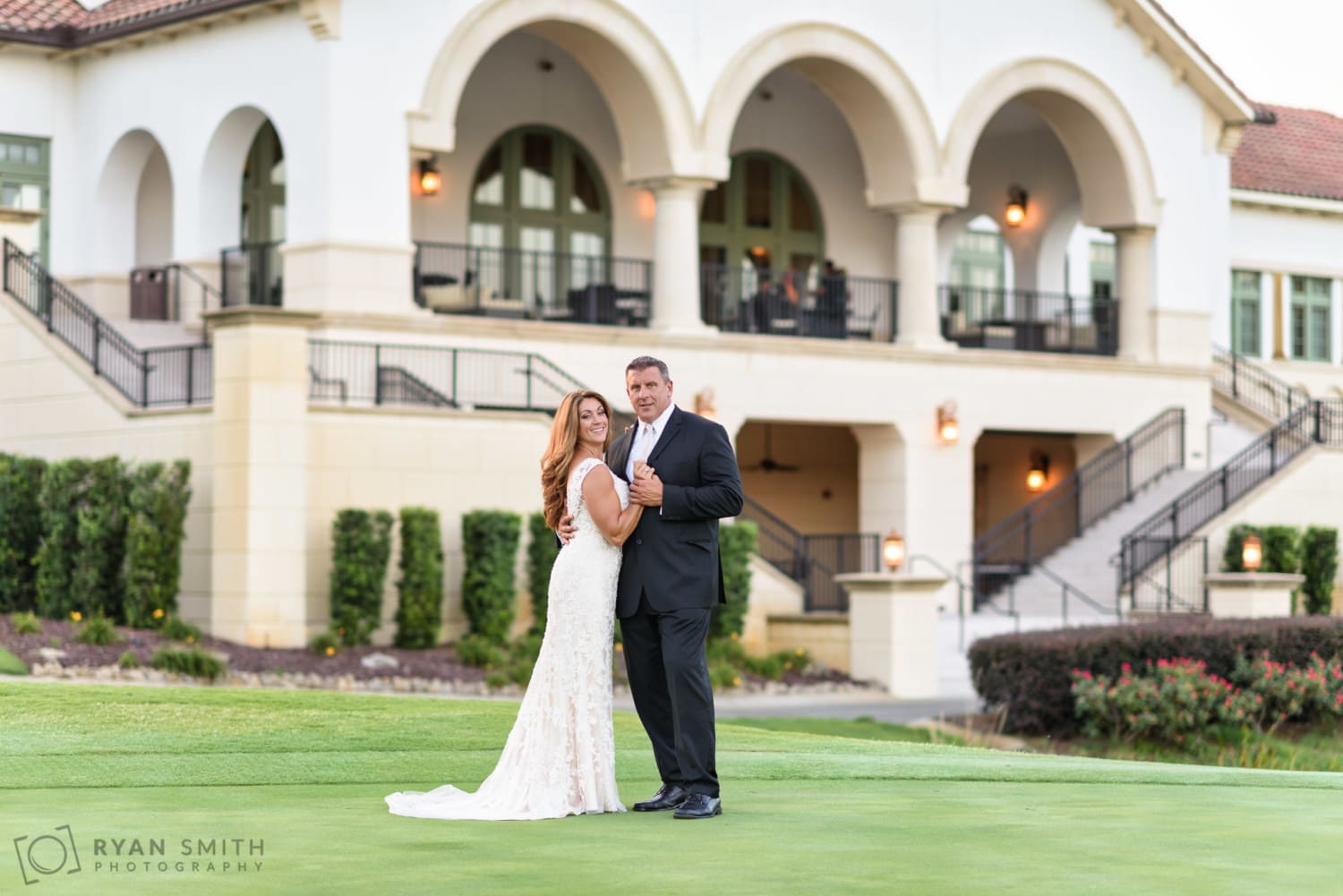Bride and groom with clubhouse in the background - Members Club at Grande Dunes