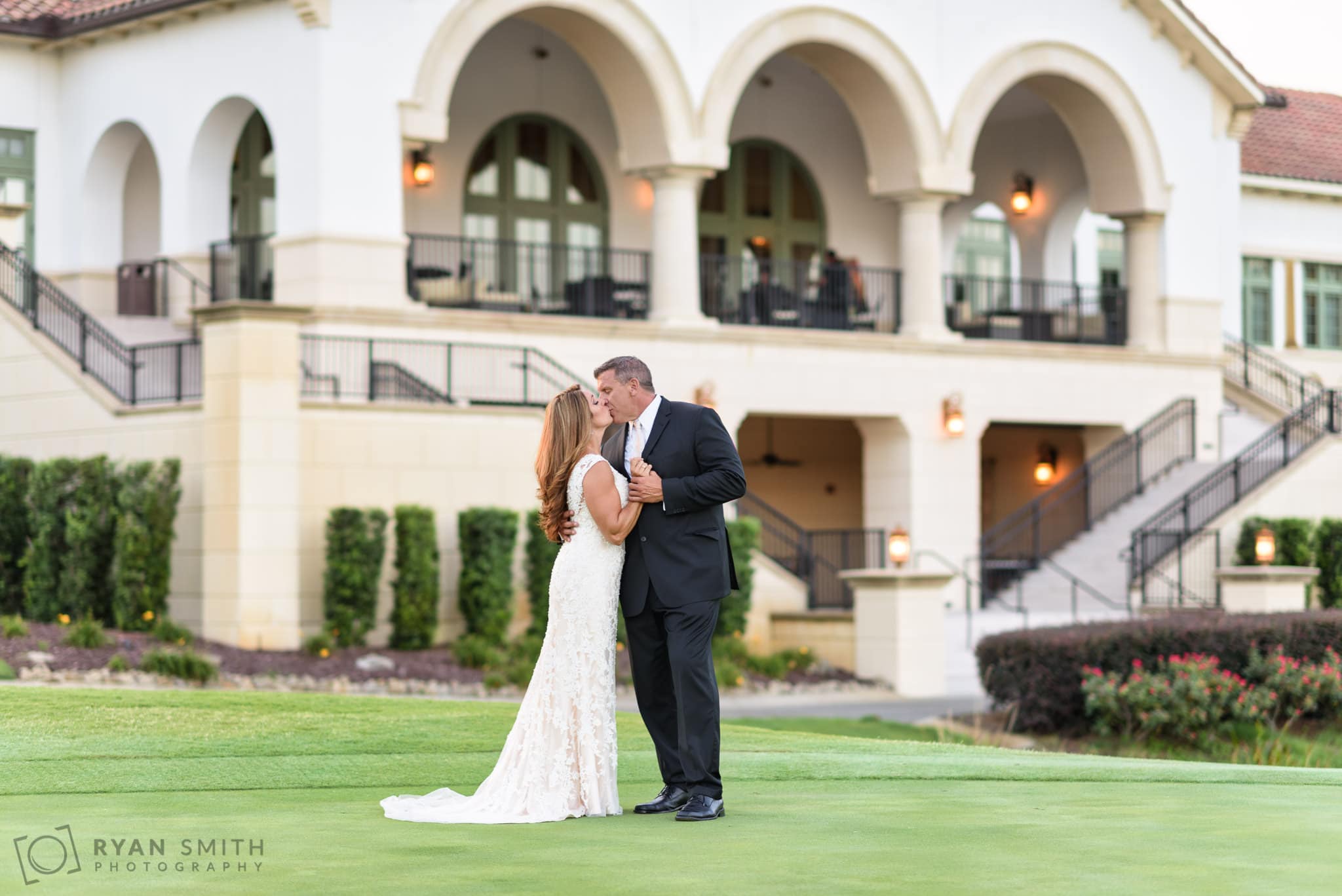 Bride and groom with clubhouse in the background - Members Club at Grande Dunes