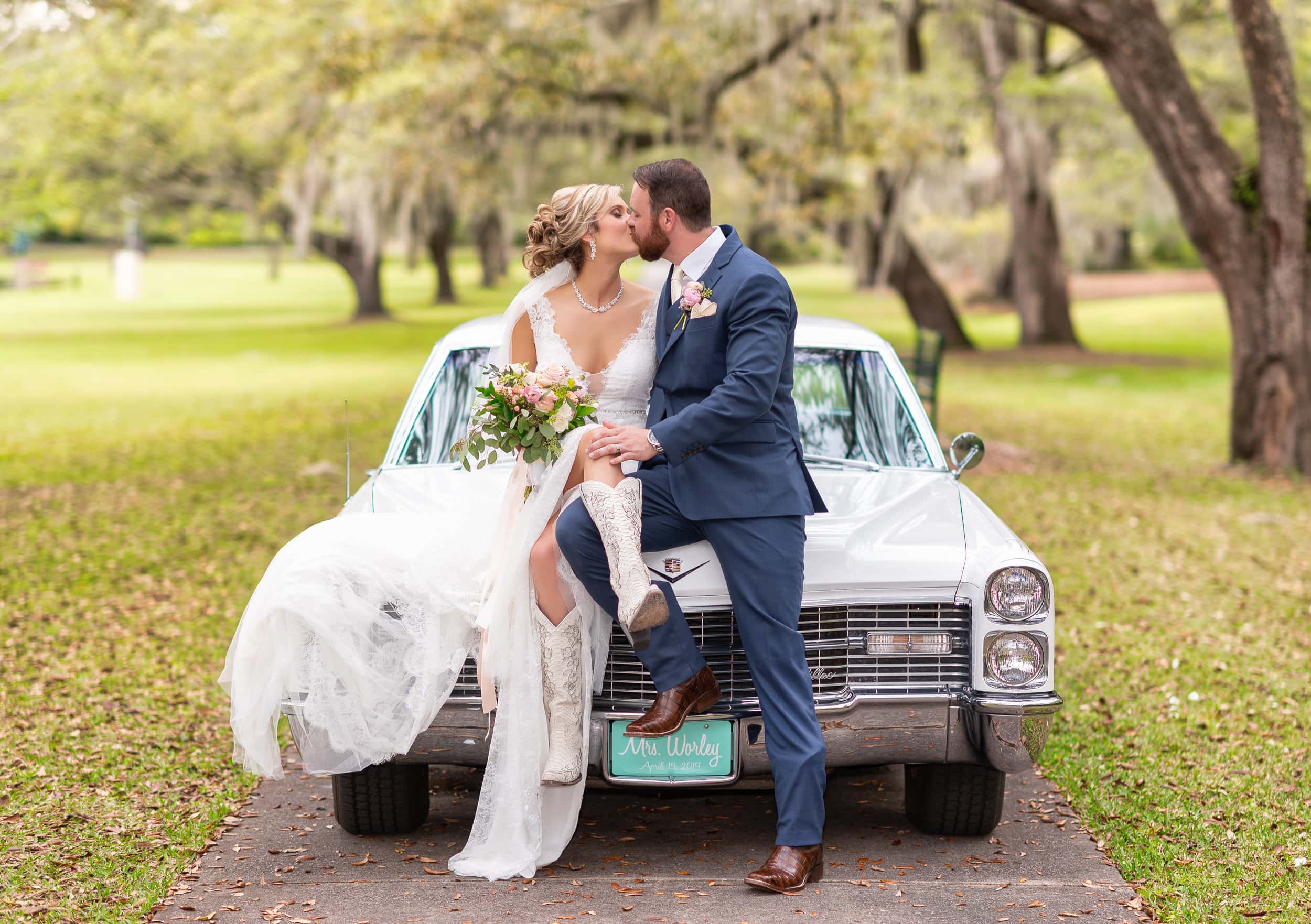 Bride and groom sitting on a classic car with cowboy boots - Brookgreen Gardens