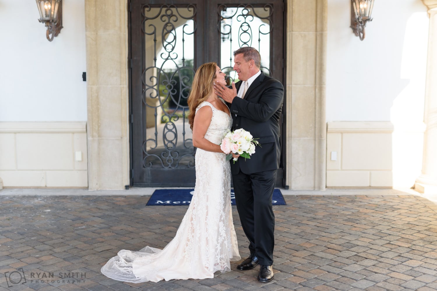 Groom touching brides face in front of the doors - Members Club at Grande Dunes