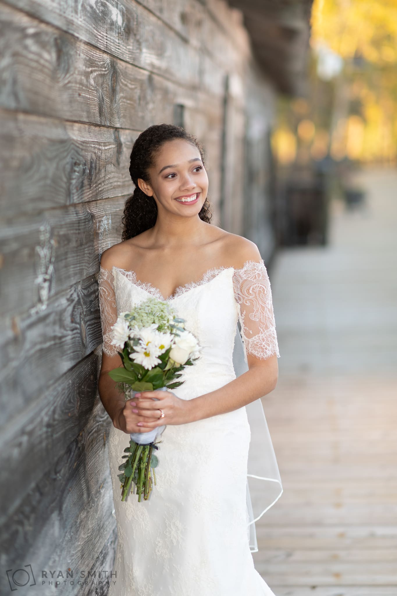 Bridal portraits leaning on the old wood of the rustic building - Conway Riverwalk