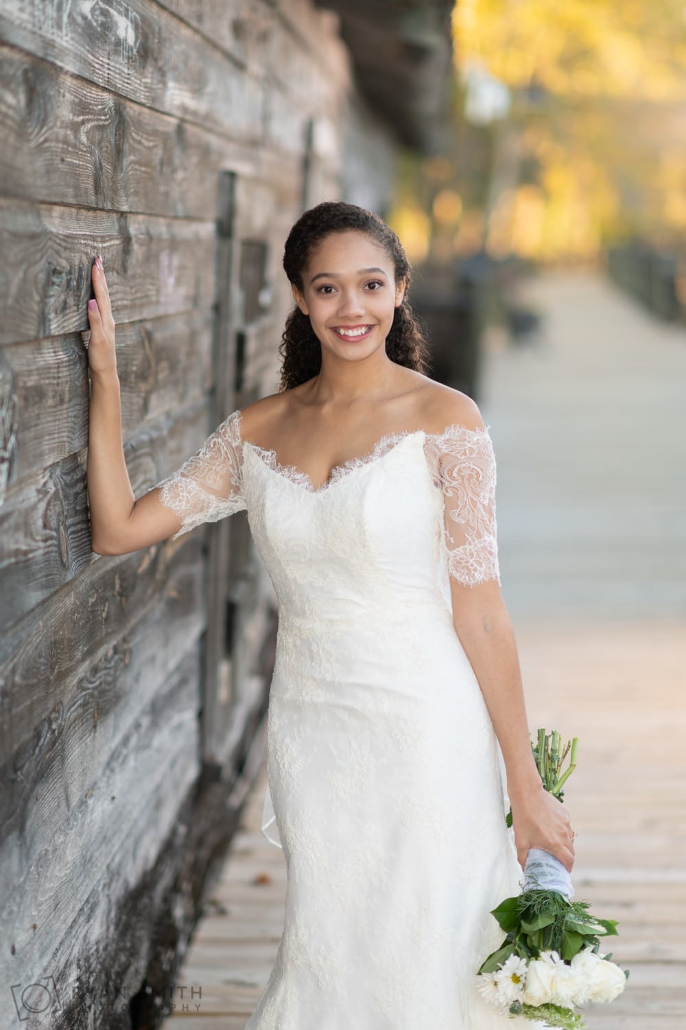 Bridal portraits leaning on the old wood of the rustic building - Conway Riverwalk