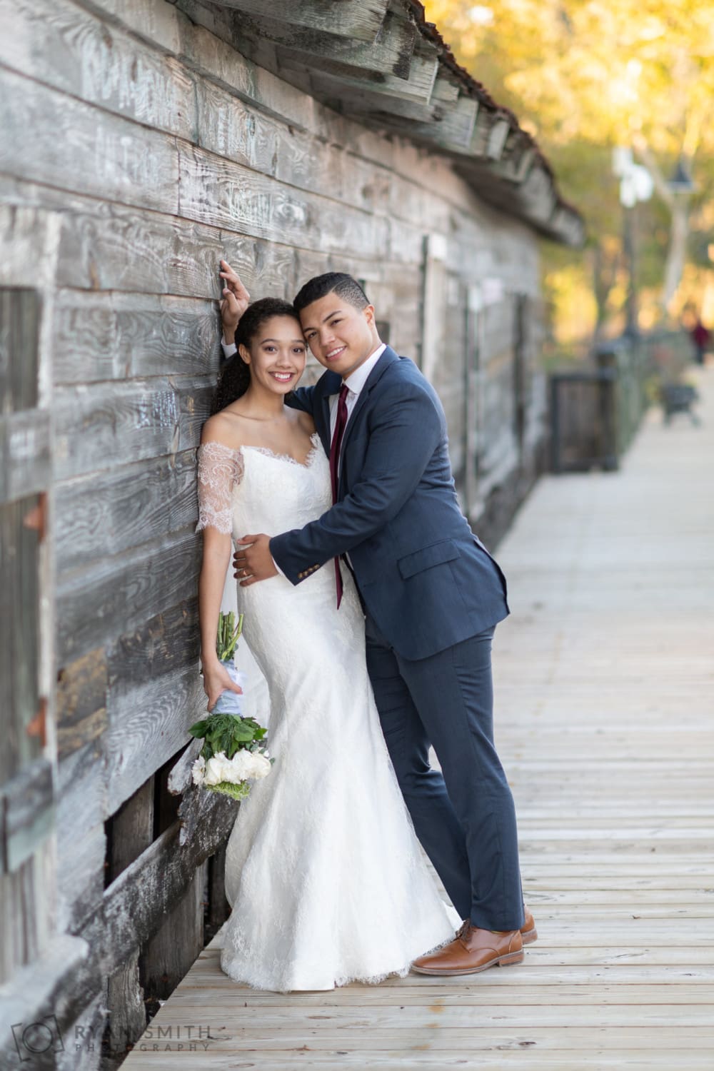 Bride and groom leaning on the rustic wood - Conway Riverwalk