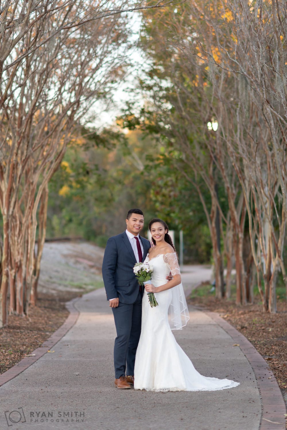 Bride and groom under the winter trees on the walkway - Conway Riverwalk