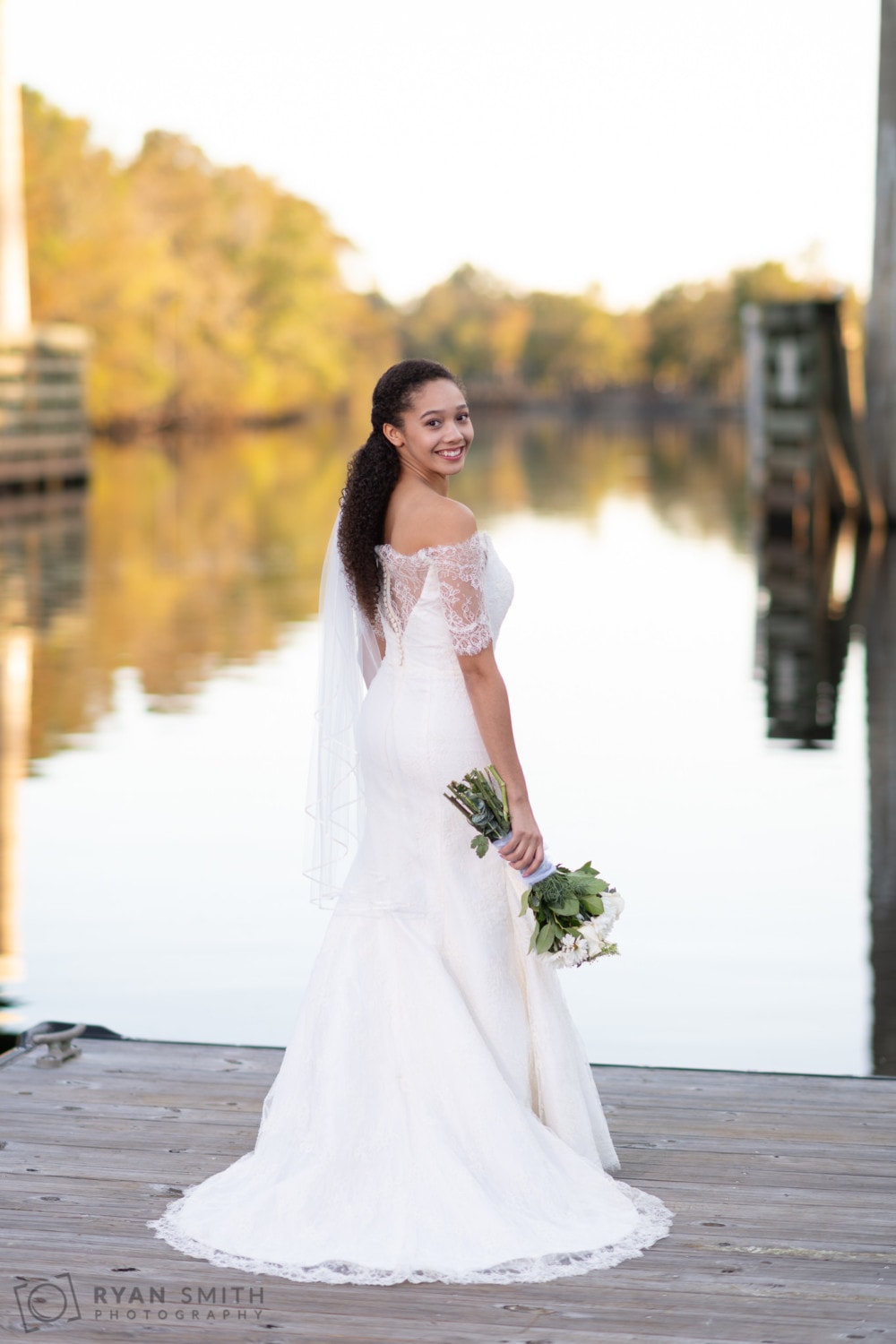Bride looking back at the camera holding flowers - Conway Riverwalk