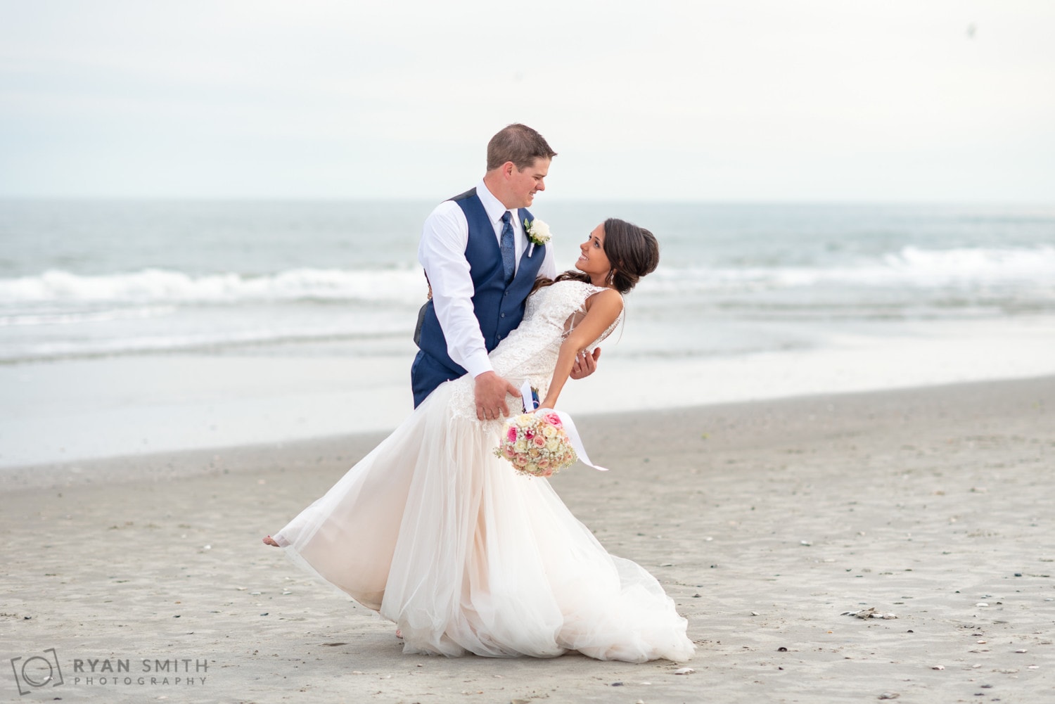 Groom dipping back bride in front of the ocean - Avista Resort - North Myrtle Beach