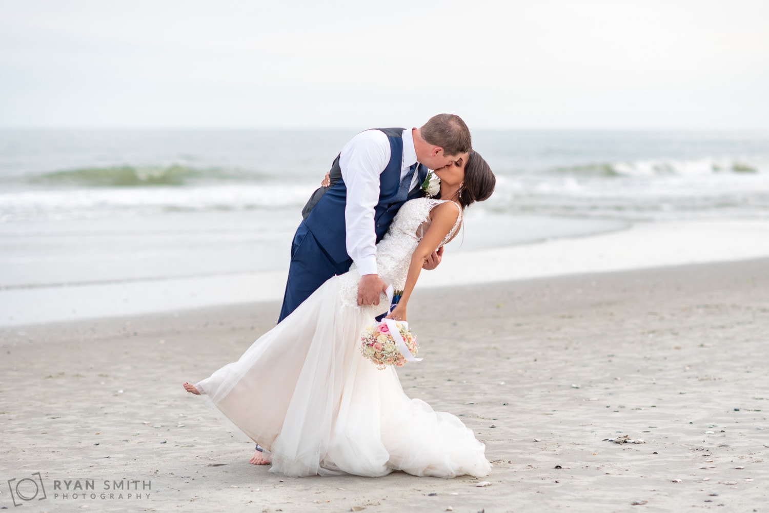 Groom dipping back bride in front of the ocean - Avista Resort - North Myrtle Beach