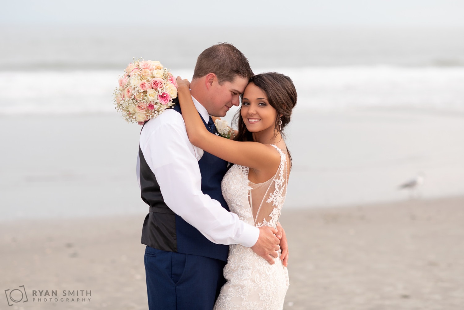 Happy couple in front of the ocean showing off the bouquet of roses - Avista Resort - North Myrtle Beach
