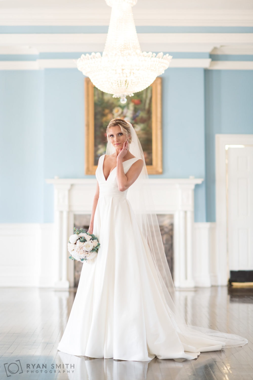 Bride touching her face in front of the fireplace - Pine Lakes Country Club