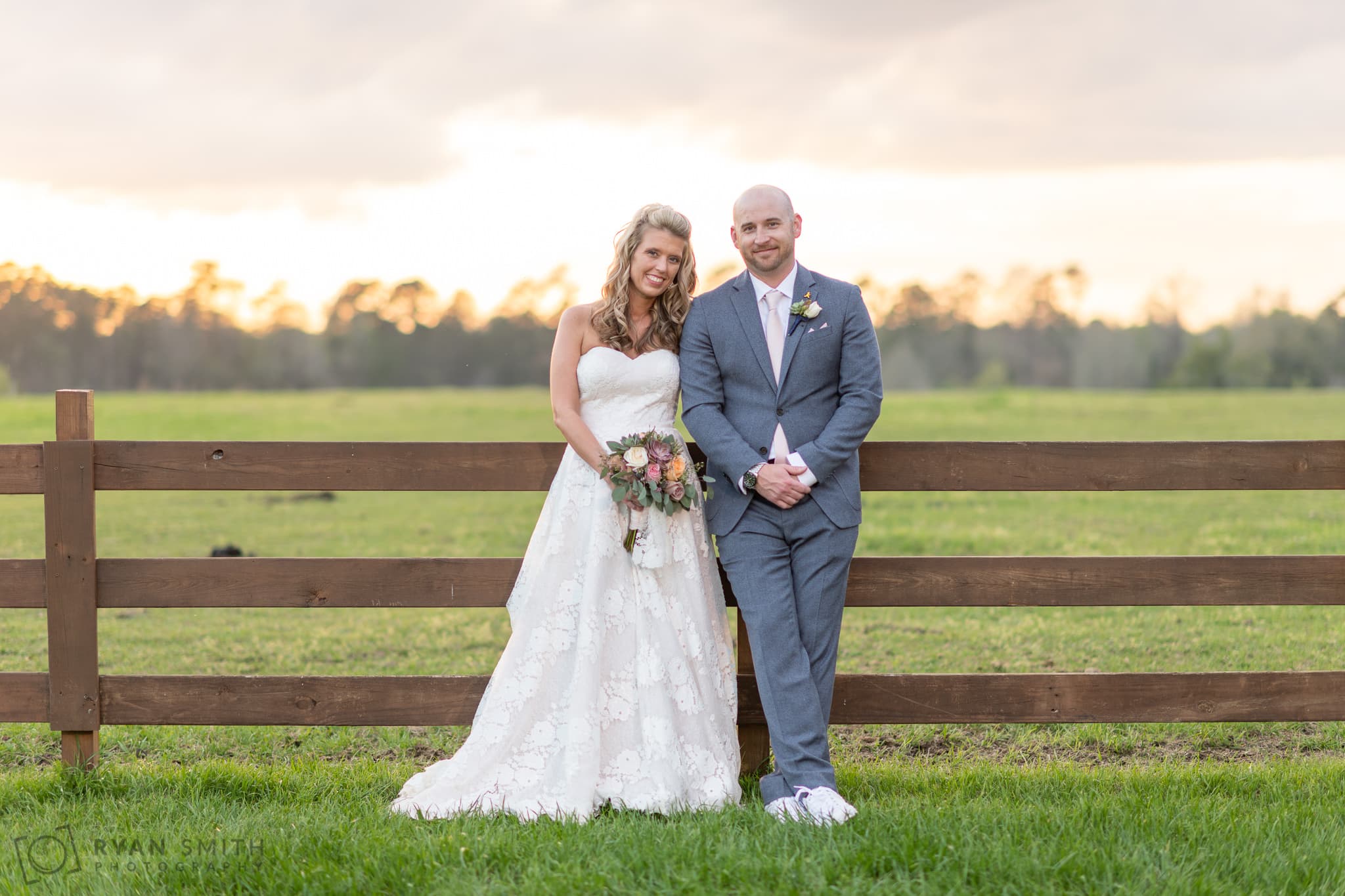 Casual portrait of the bride and groom leaning against the fence  - Wildhorse at Parker Farms