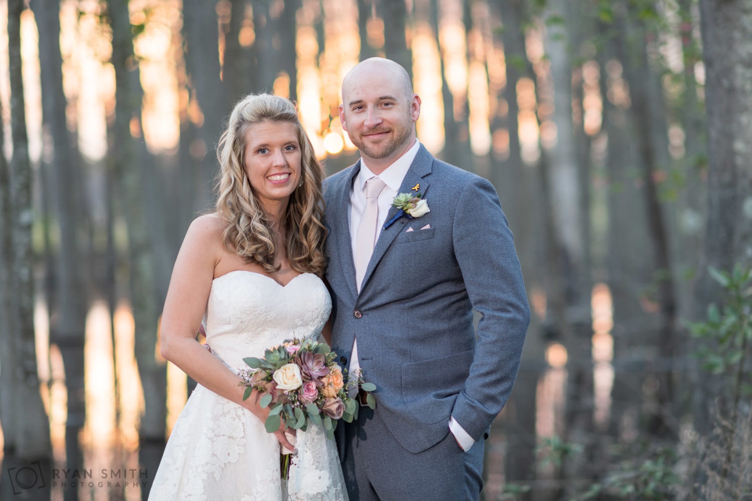Couple smiling in from of the sunlight filtering through the trees - Wildhorse at Parker Farms