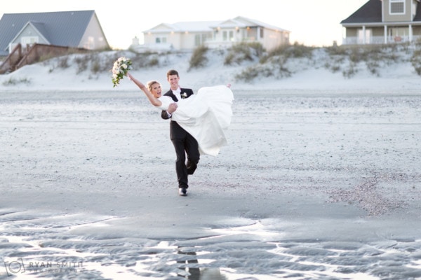 Groom carrying bride to the ocean