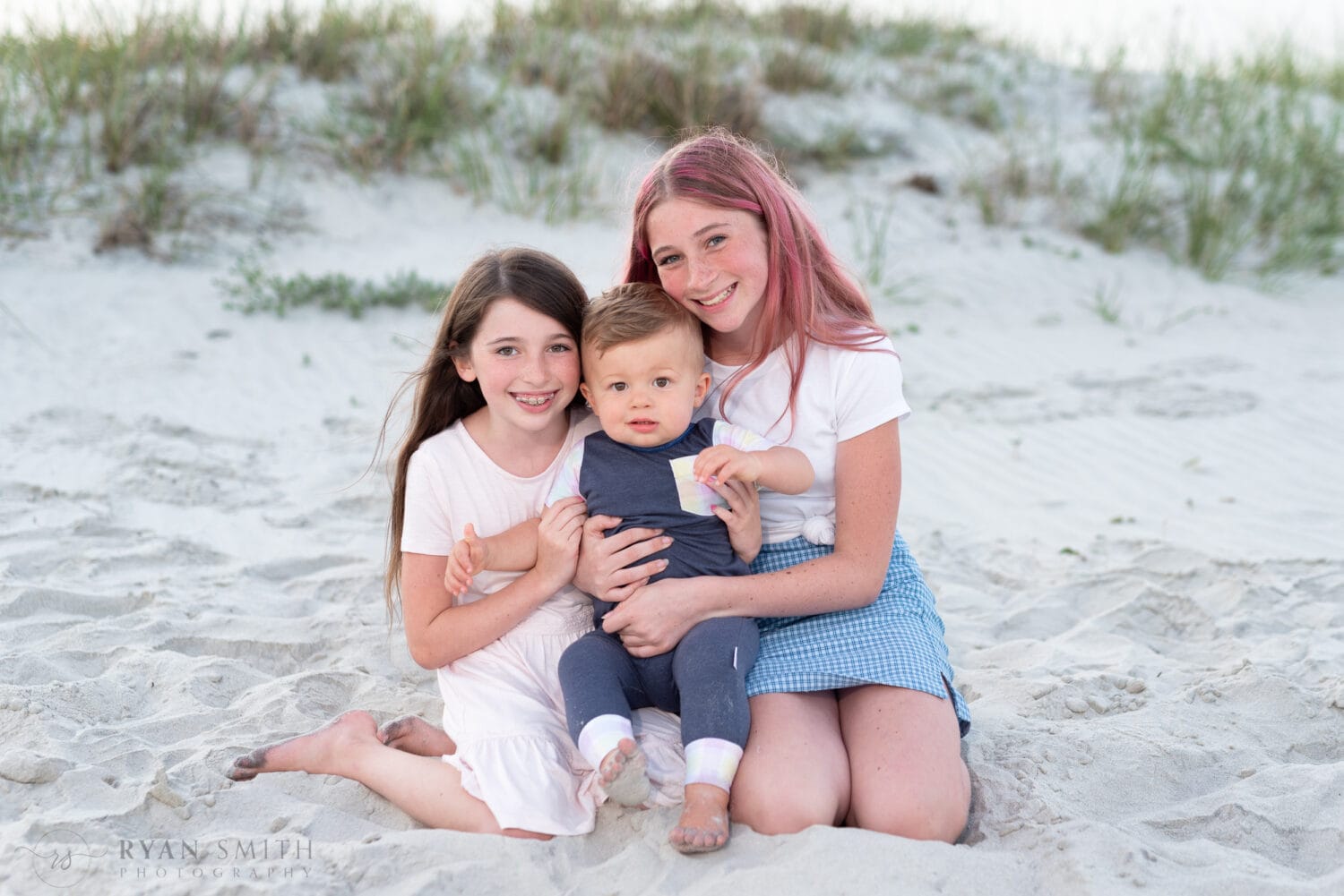 Two sisters holding their little brother by the dunes - Huntington Beach State Park
