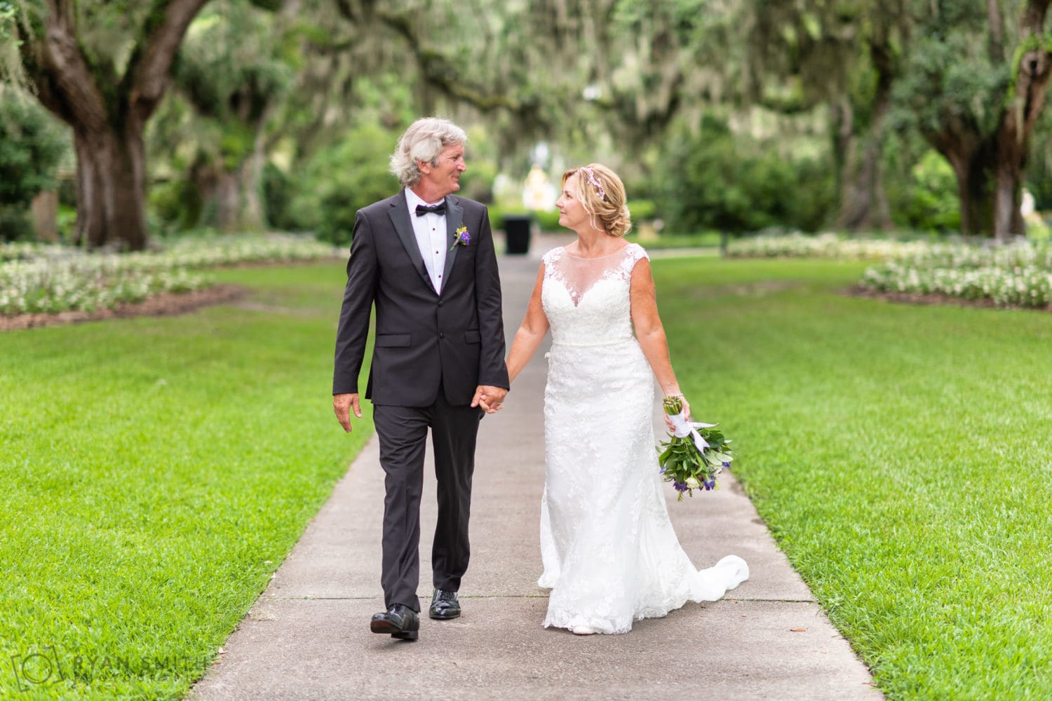 Bride and groom walking under the oaks - Live Oak Allee - Brookgreen Gardens