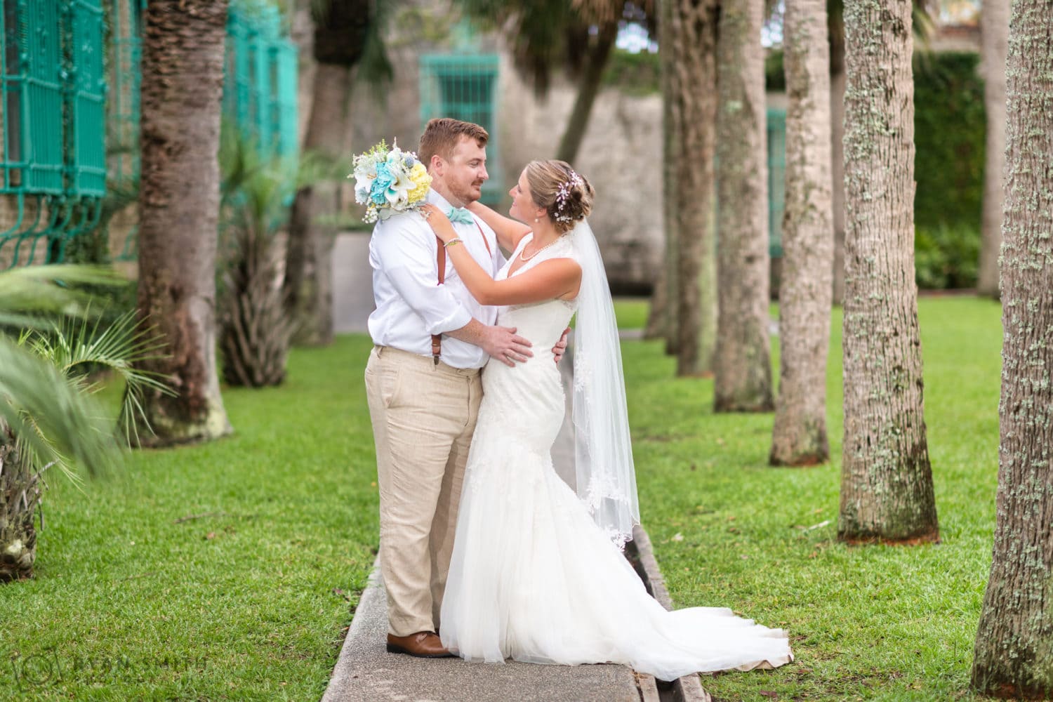 Bride and groom by the palms in the courtyard - Atalaya Castle - Huntington Beach State Park