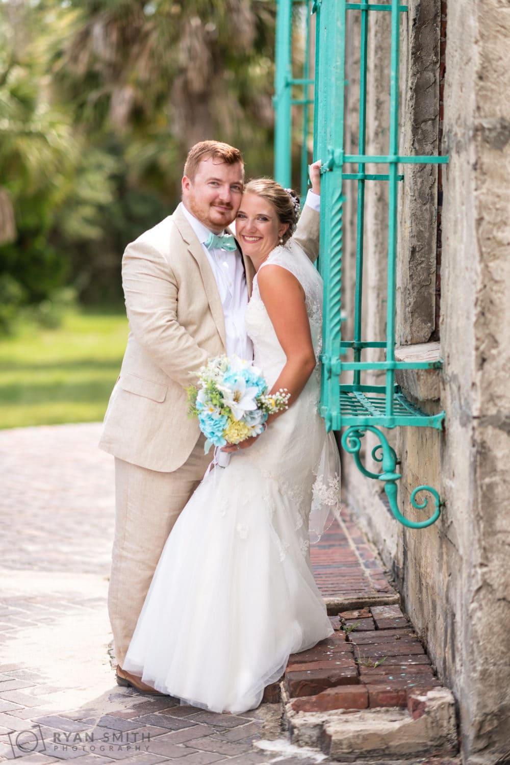 Bride and groom leaning on the castle wrought iron windows - Atalaya Castle - Huntington Beach State Park