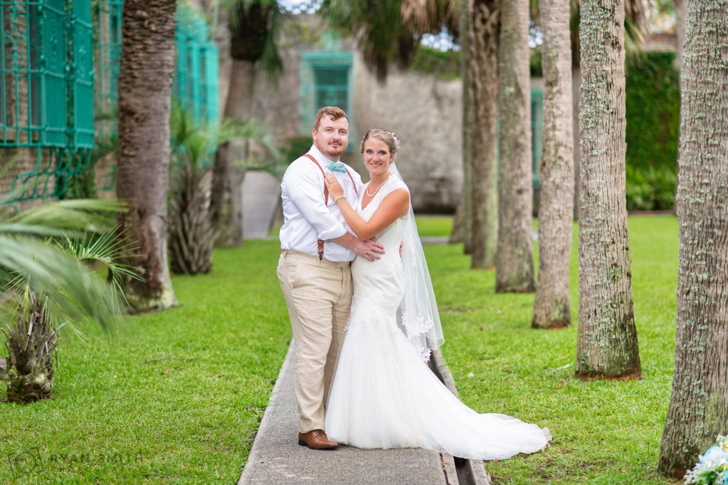 Bride and groom standing under the palm trees -