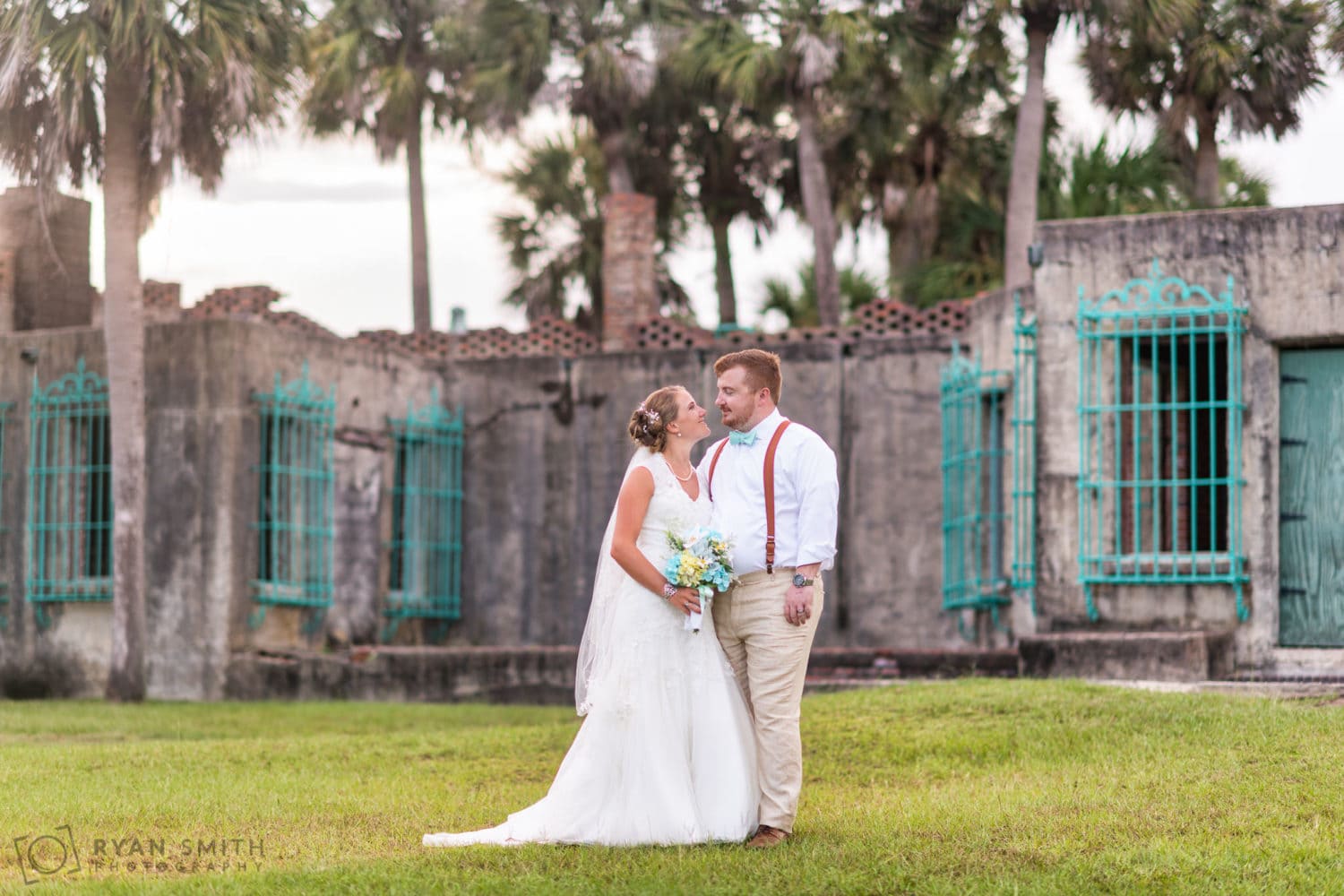 Bride looking into the eyes of the groom behind the castle - Atalaya Castle - Huntington Beach State Park