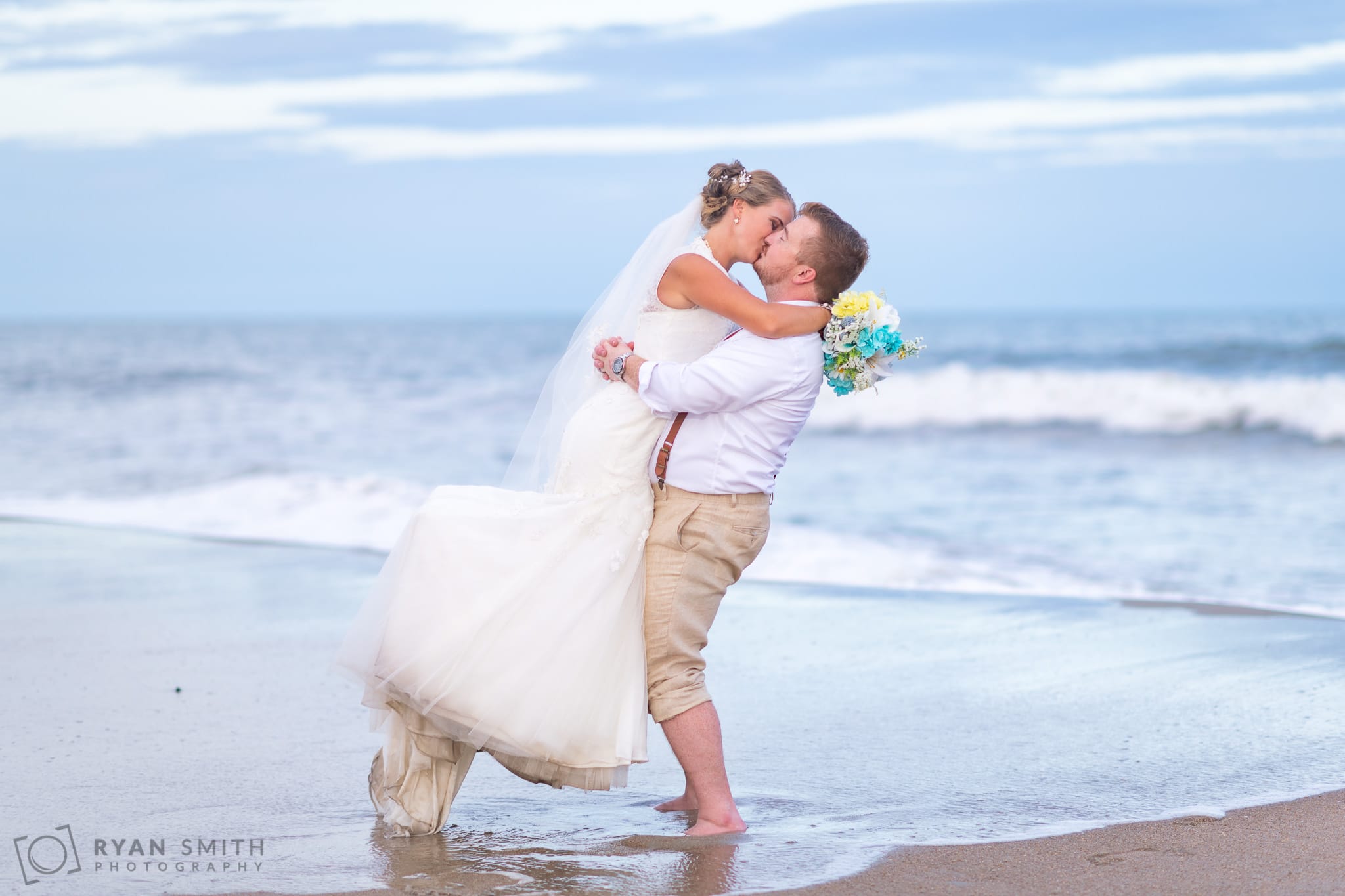 Groom lifting bride up just as the wave comes in - Atalaya Castle - Huntington Beach State Park