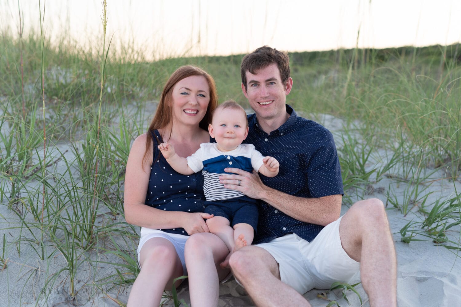 Mom and dad with smiling baby boy sitting by the dunes - Huntington Beach State Park