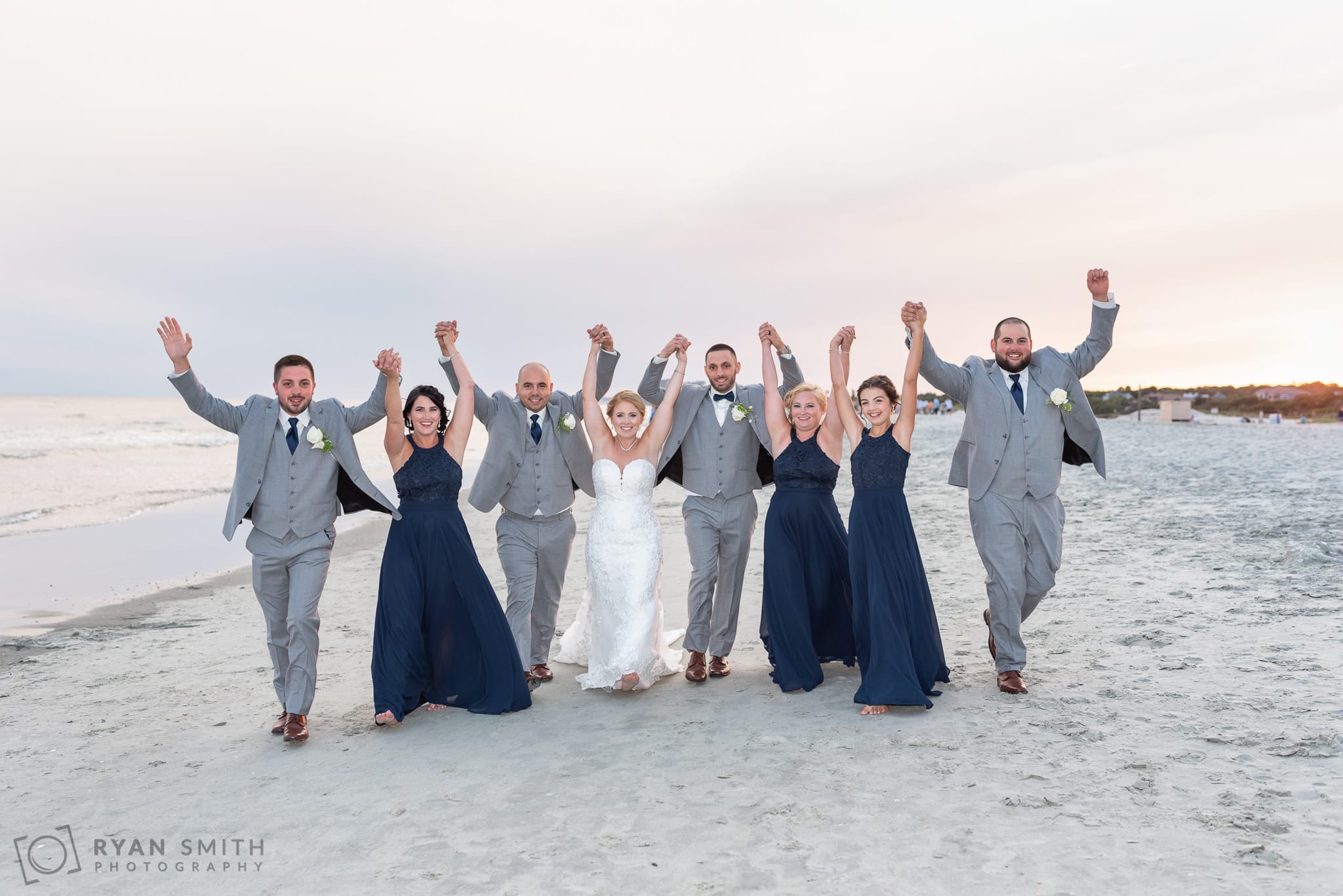 Bridal party walking down the beach with hands in the air - 21 Main Events - North Myrtle Beach