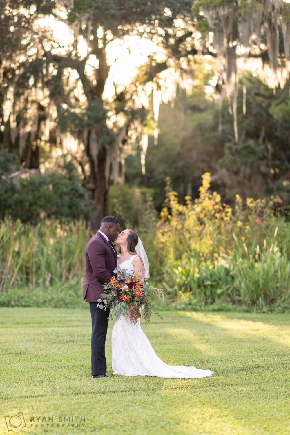 Bride and groom in front of the sunset filtering through the oaks - Magnolia Plantation - Charleston, SC