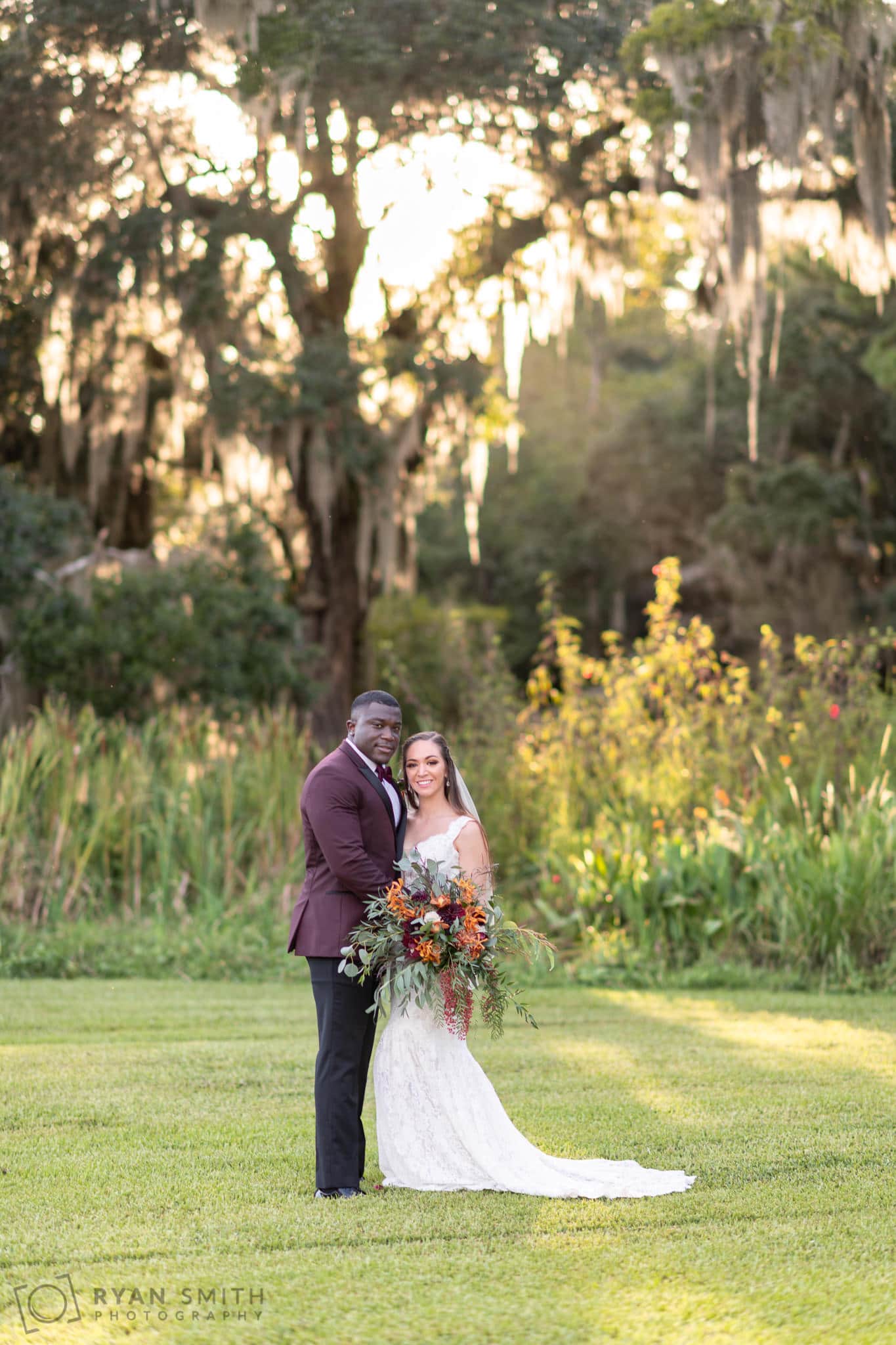 Bride and groom in front of the sunset filtering through the oaks - Magnolia Plantation - Charleston, SC