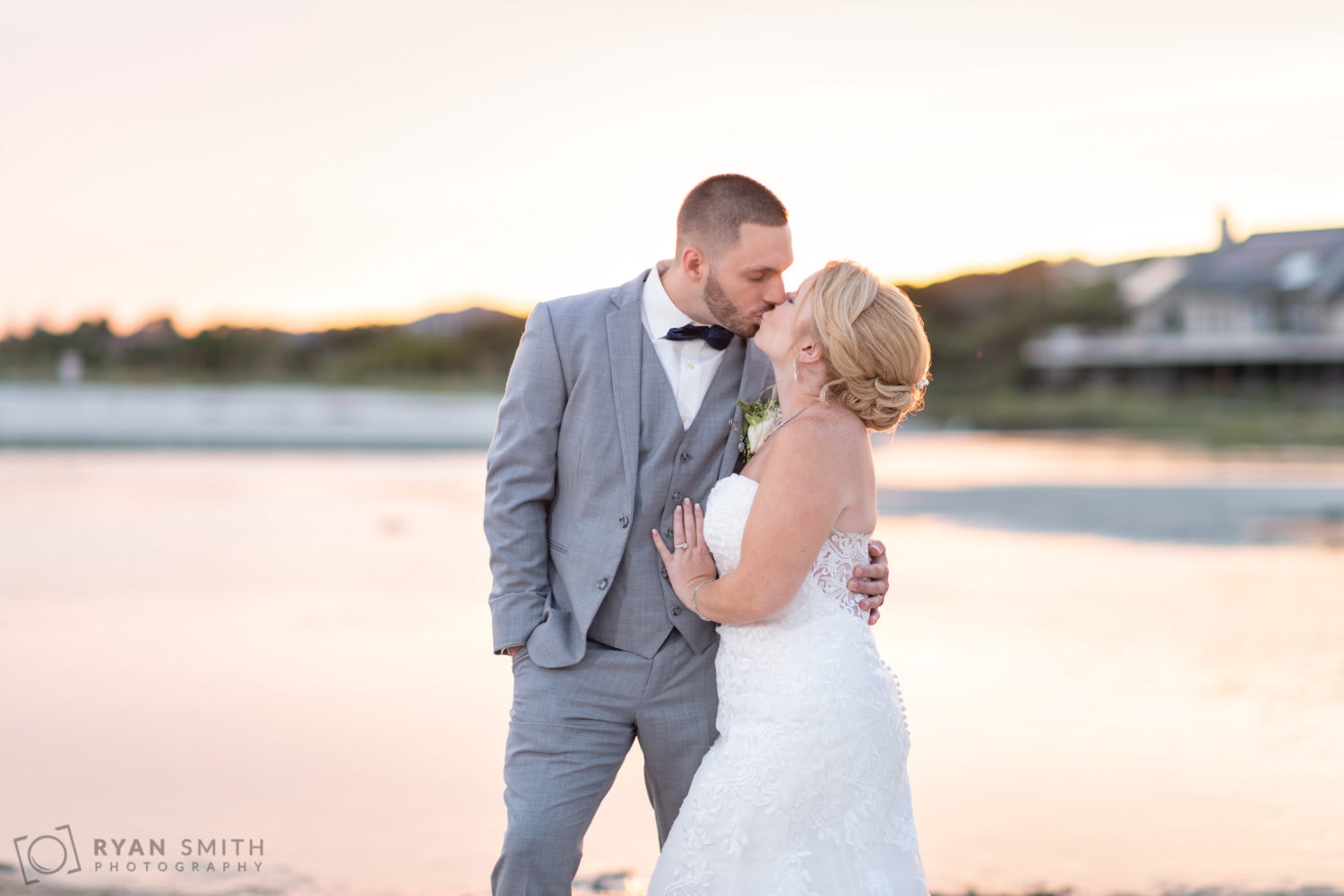 Bride and groom kissing in front of the inlet backlit by sunset - 21 Main Events - North Myrtle Beach