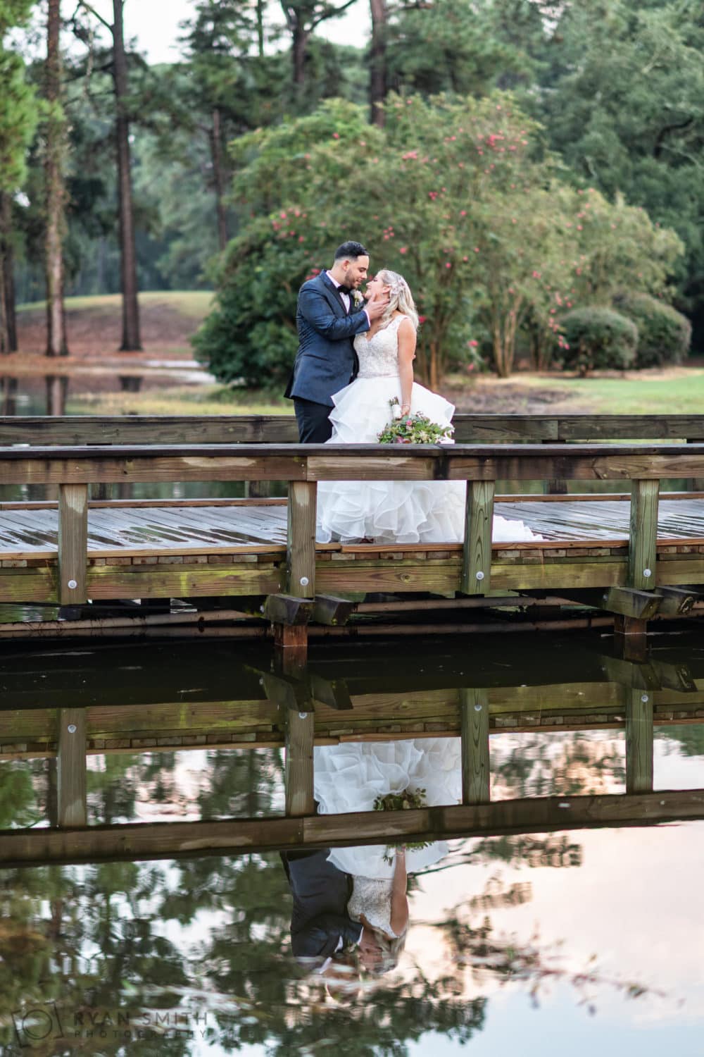 Bride and groom standing on the bridge reflecting in the water - Litchfield Country Club