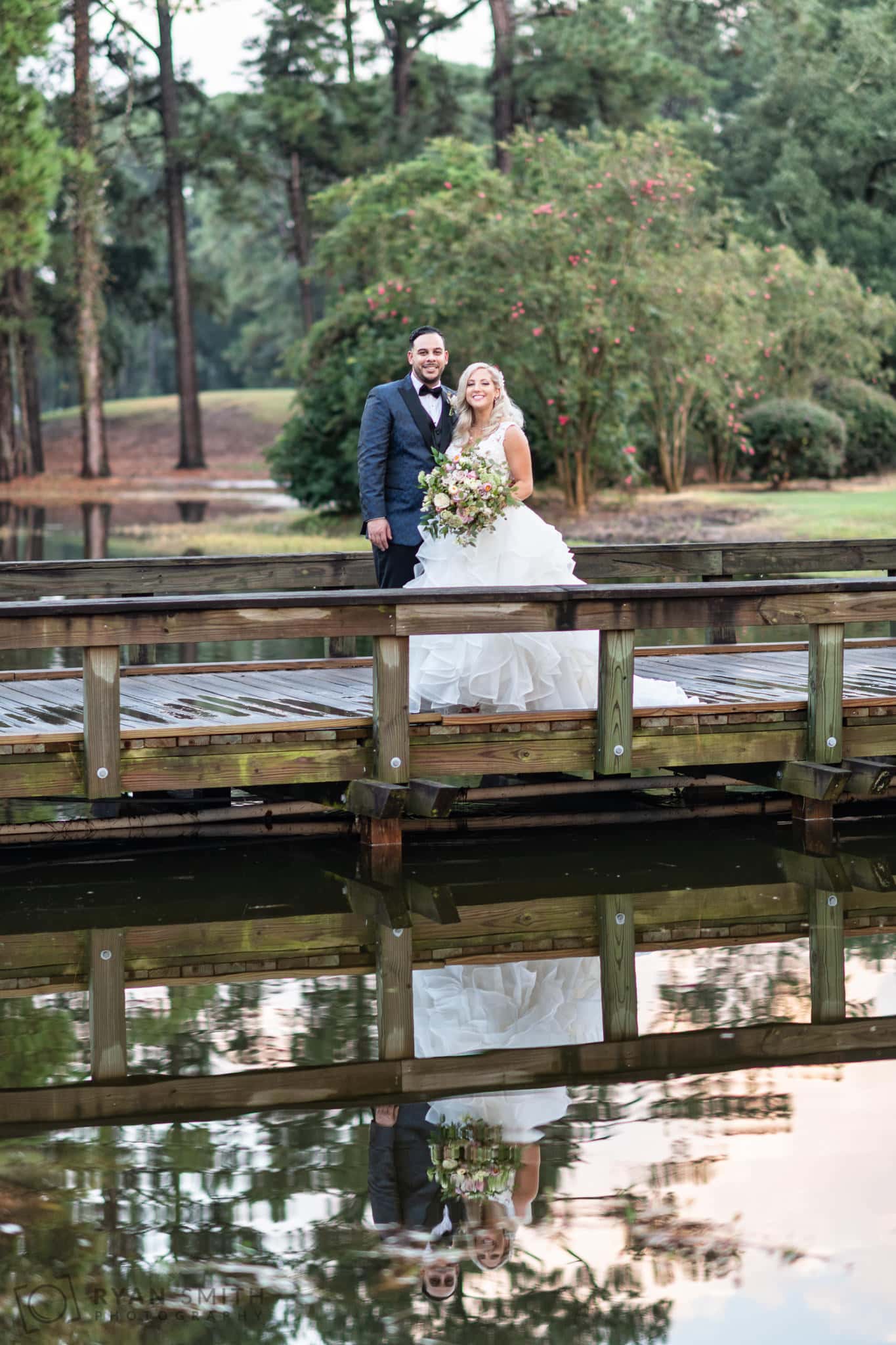 Bride and groom standing on the bridge reflecting in the water - Litchfield Country Club