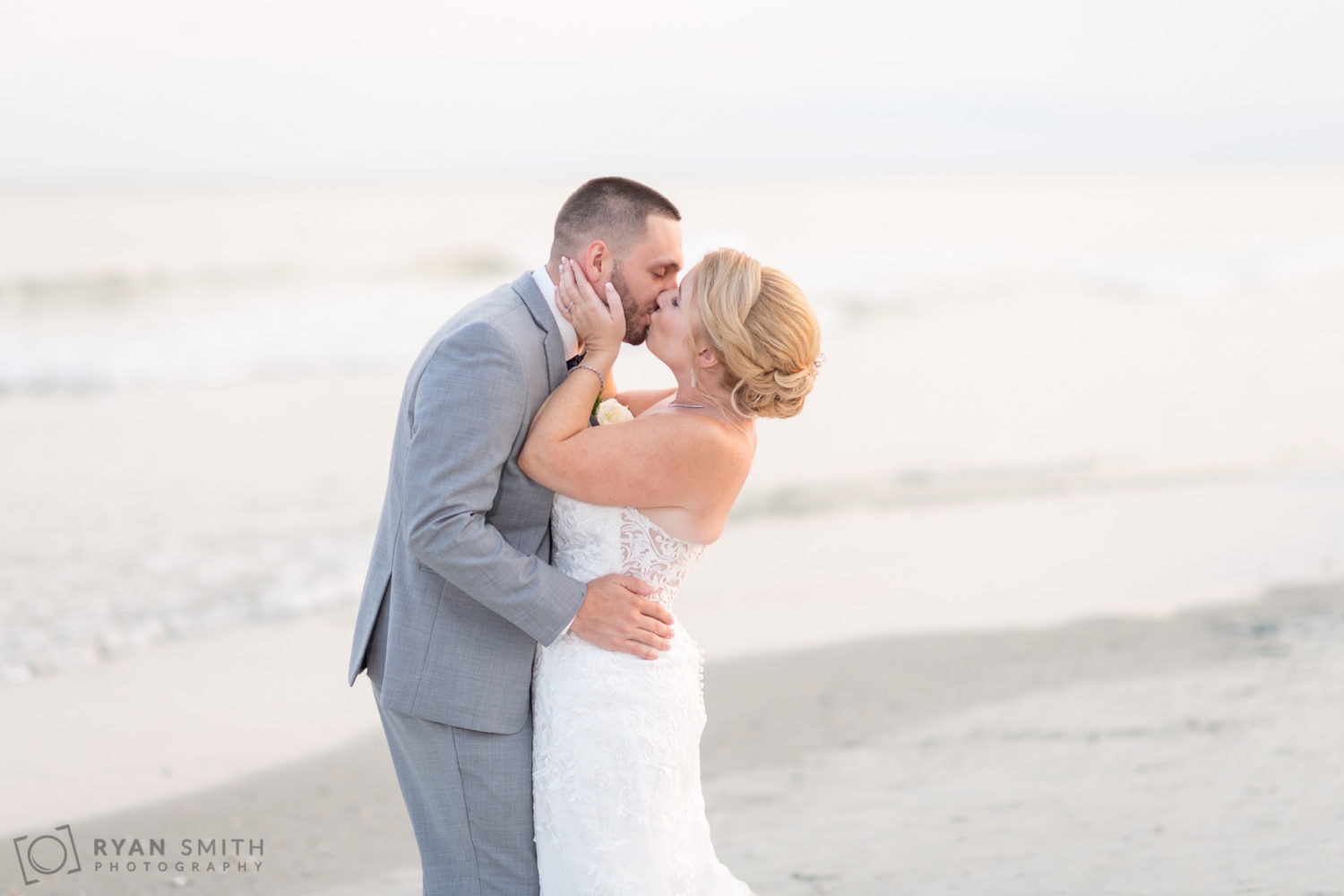 Bride pulling groom in for a kiss in front of the ocean - 21 Main Events - North Myrtle Beach