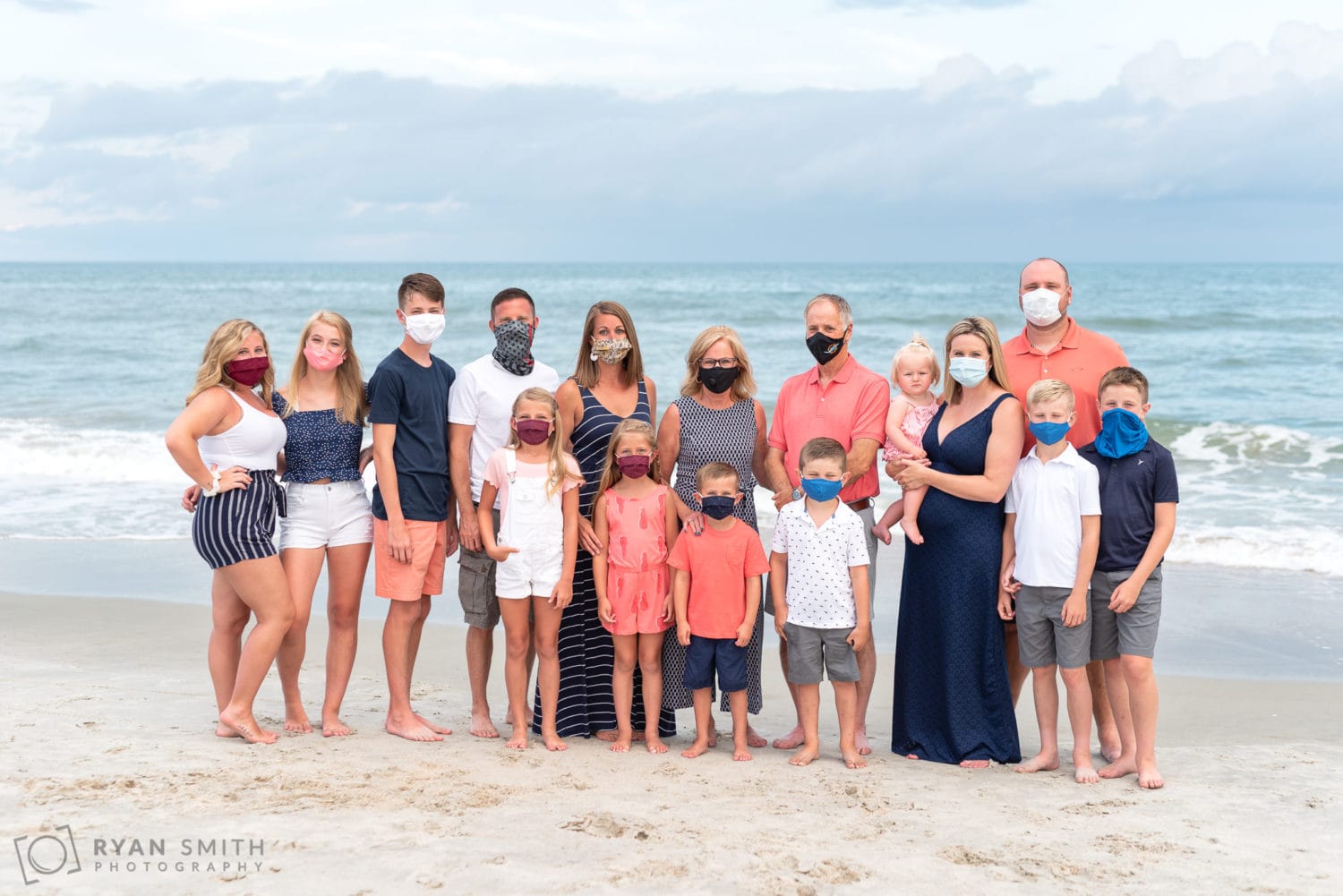 Family posing with their masks in front of the ocean - Huntington Beach State Park