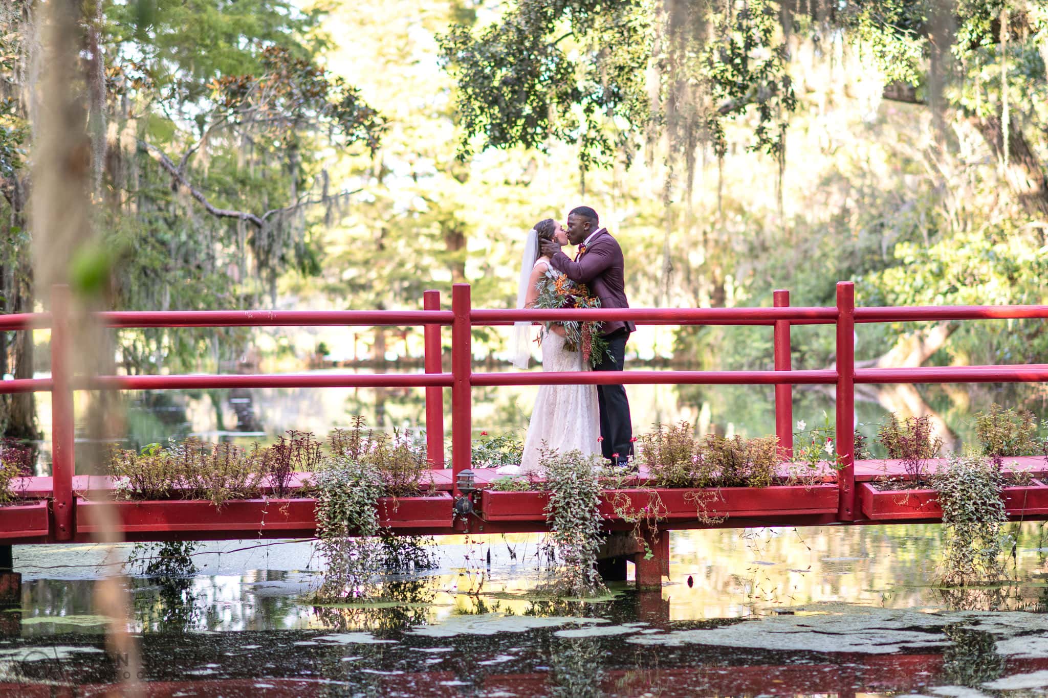 Portraits of bride and groom on the red bridge overlooking the lake - Magnolia Plantation - Charleston, SC