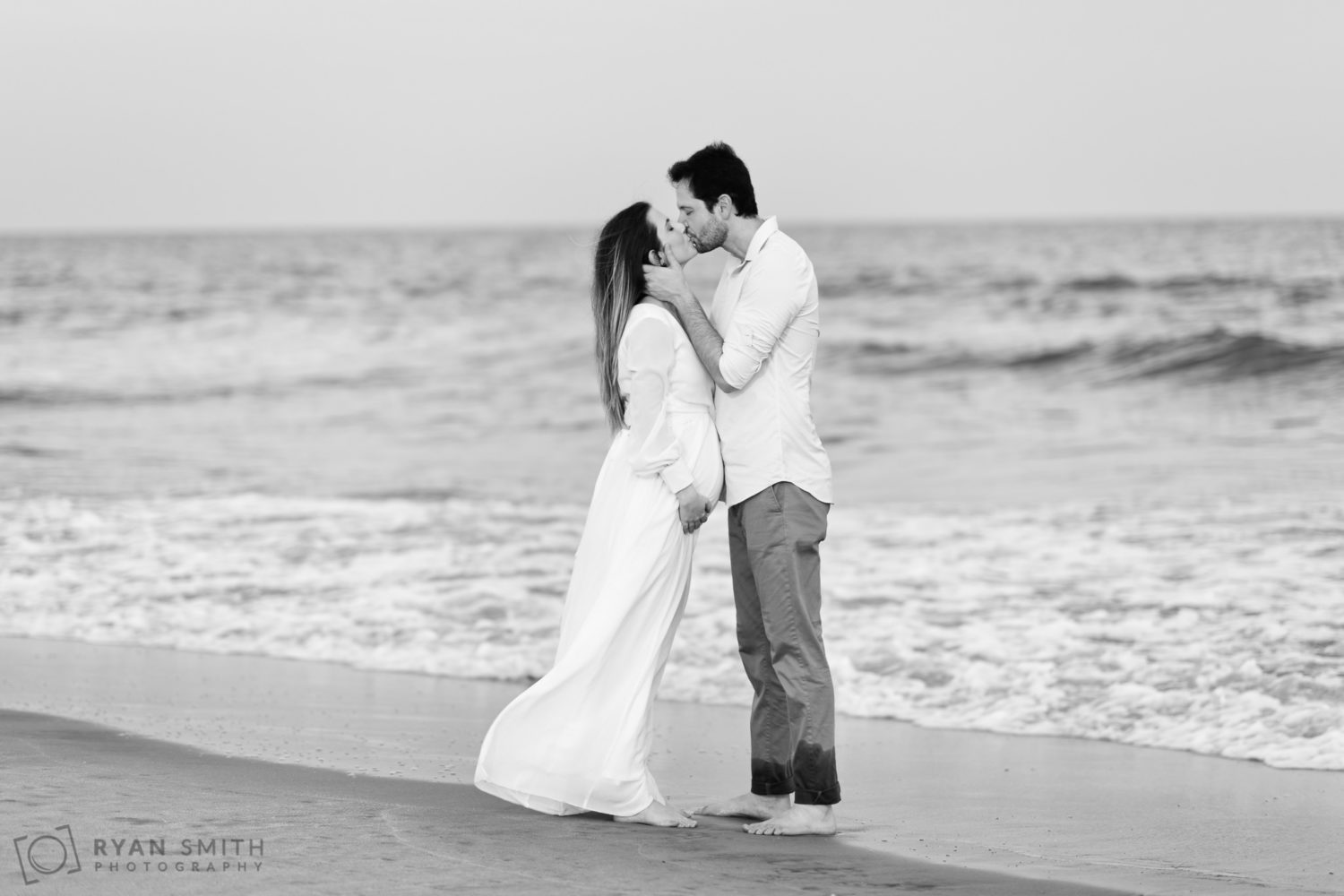 Black and white portraits of husband and expecting mother in front of the ocean - Huntington Beach State Park