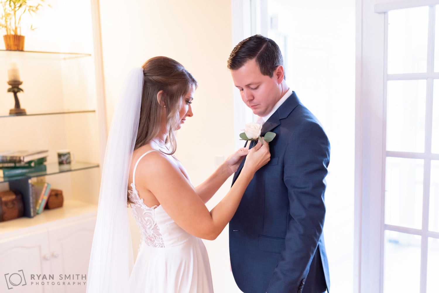 Bride helping groom with boutonniere  - Wachesaw Plantation