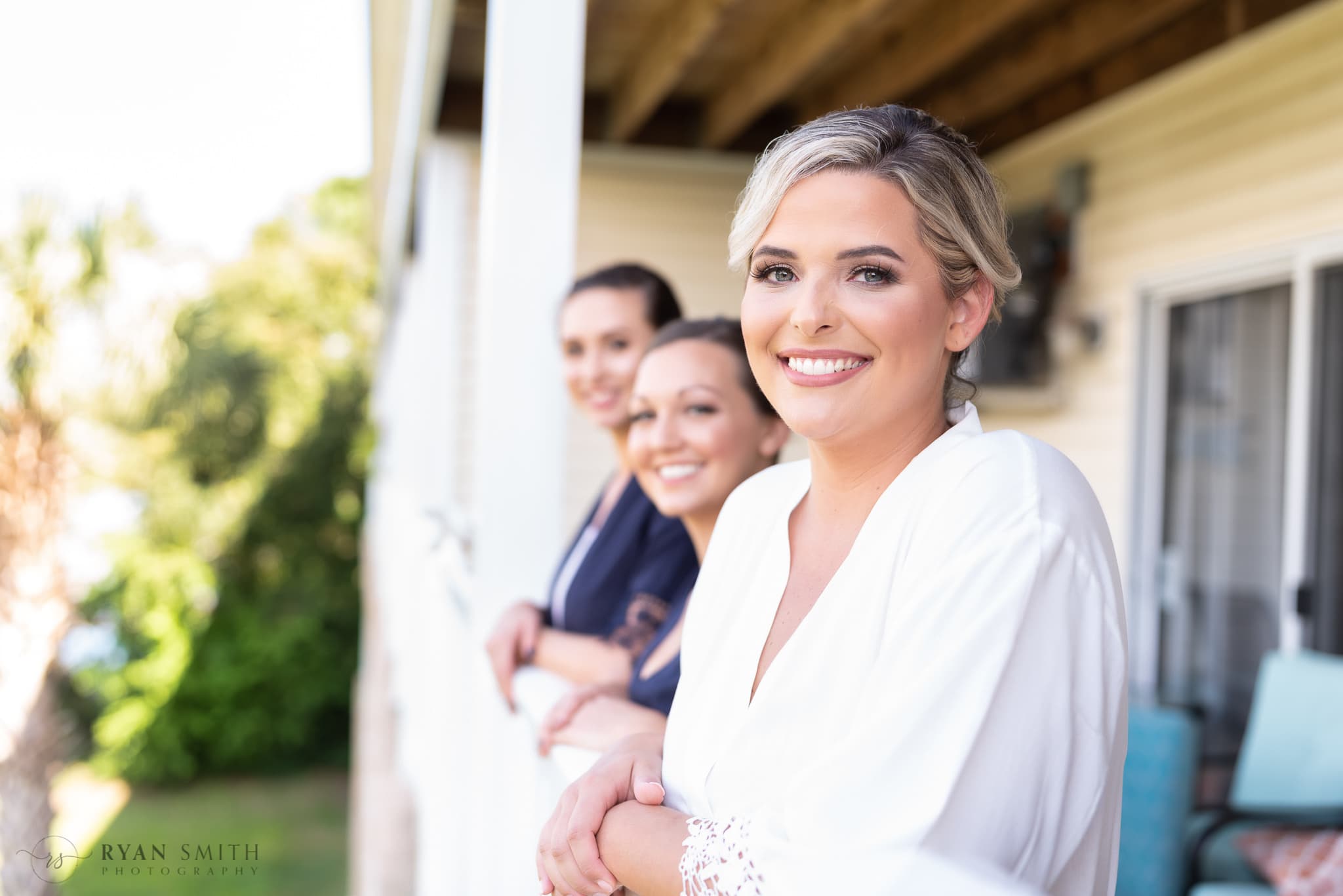 Bride and bridesmaids looking out over the balcony - Folly Beach - Charleston